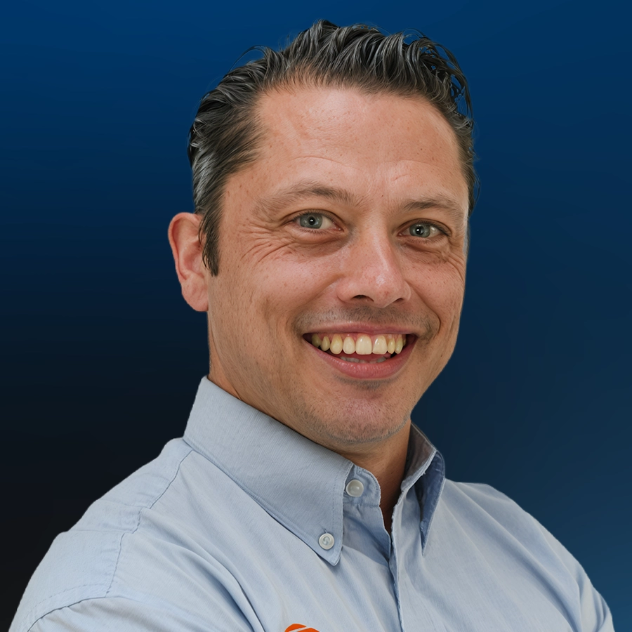 Professional headshot of smiling man wearing light blue button-up shirt
