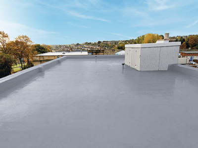 Smooth grey flat roof with liquid waterproofing membrane and low parapet walls overlooking trees and buildings