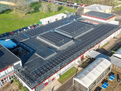 Aerial view of a large building with solar panels covering its flat roof