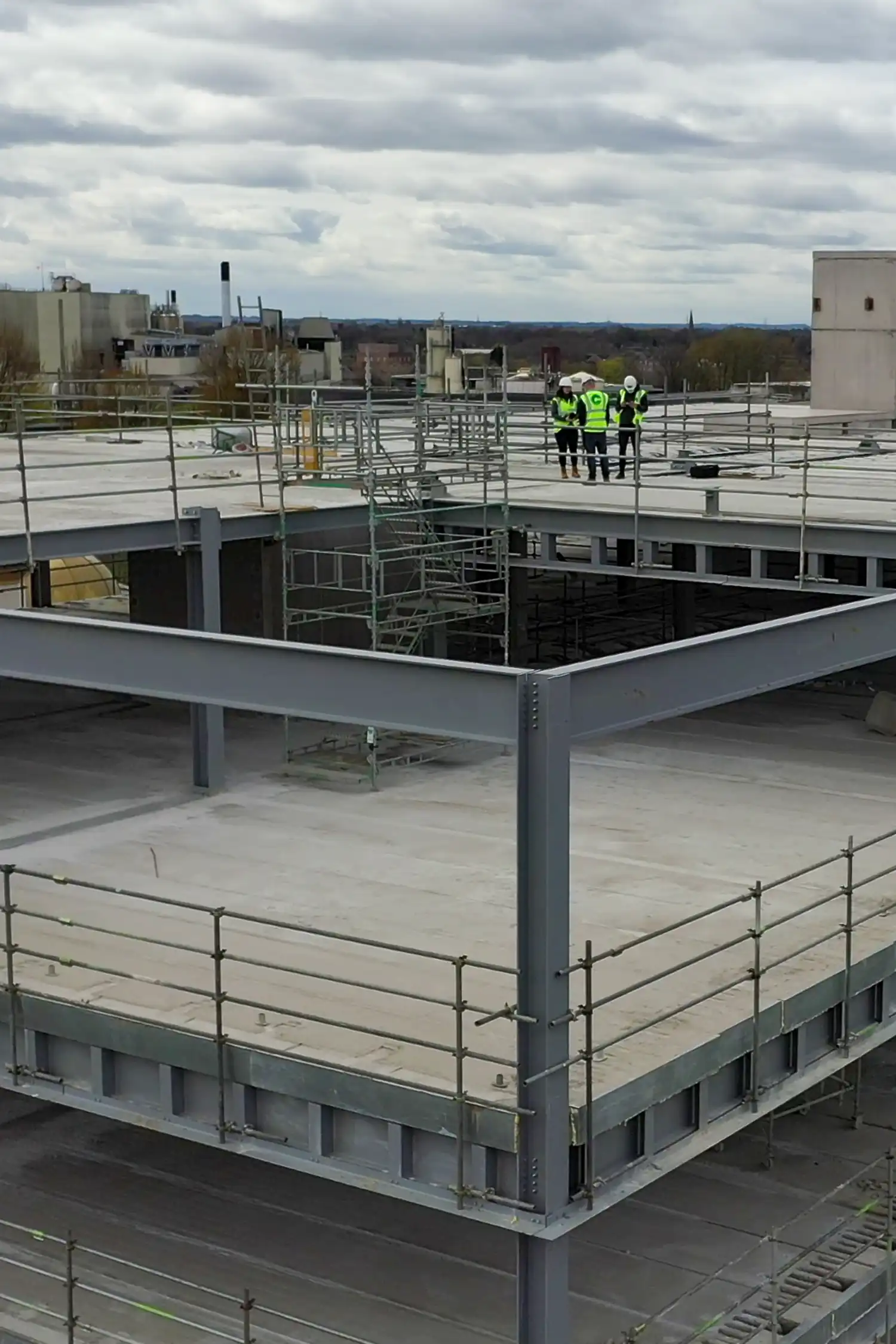 Construction workers in safety vests on multi-level concrete building roof structure