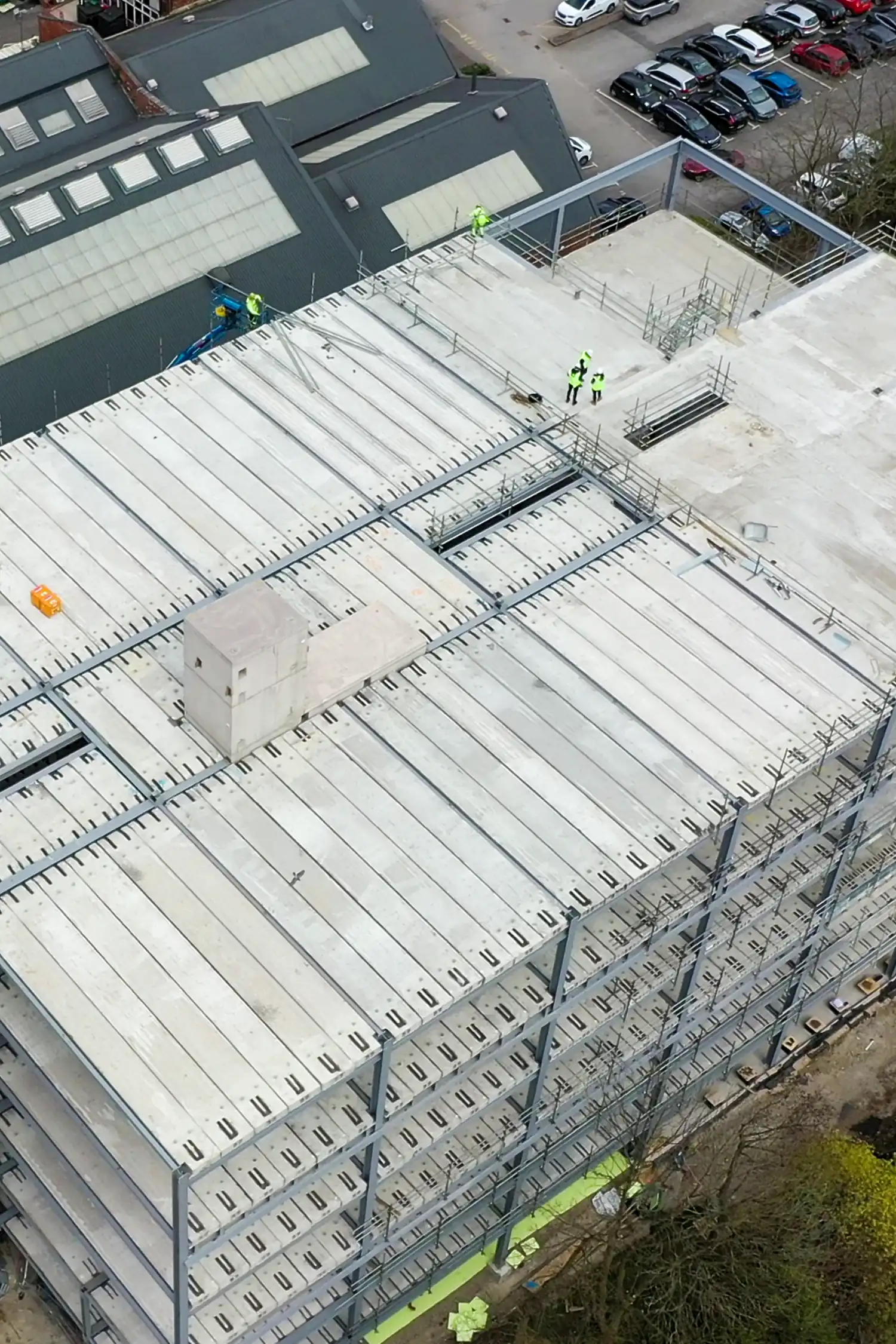 Aerial view construction workers installing white roof decking system on building structure