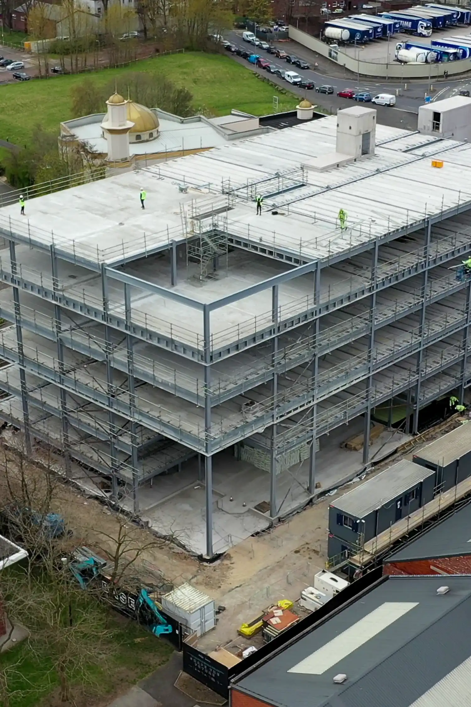 Aerial view of multi-story concrete parking structure under construction with steel framework