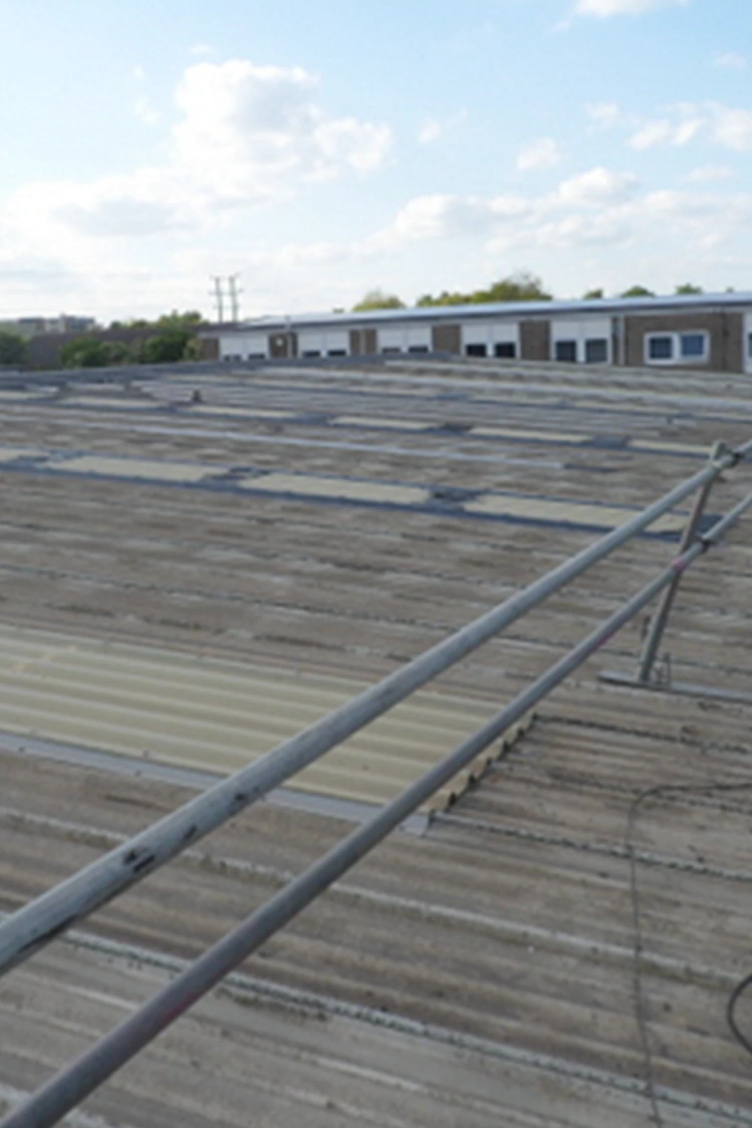 Standing seam metal roof with industrial building and safety railings visible