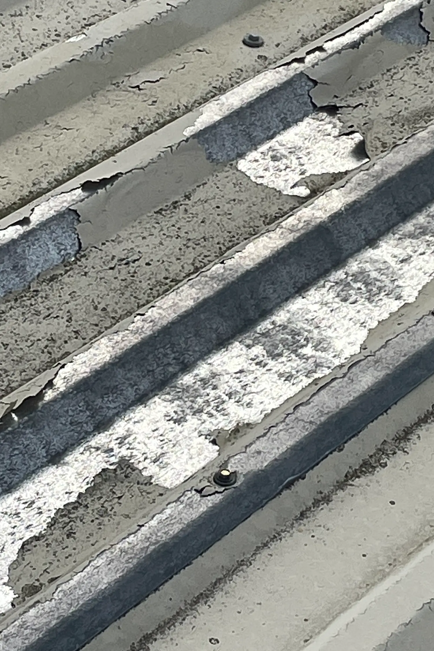 Concrete roof channels with white paint stripes and dark metal flashing strips