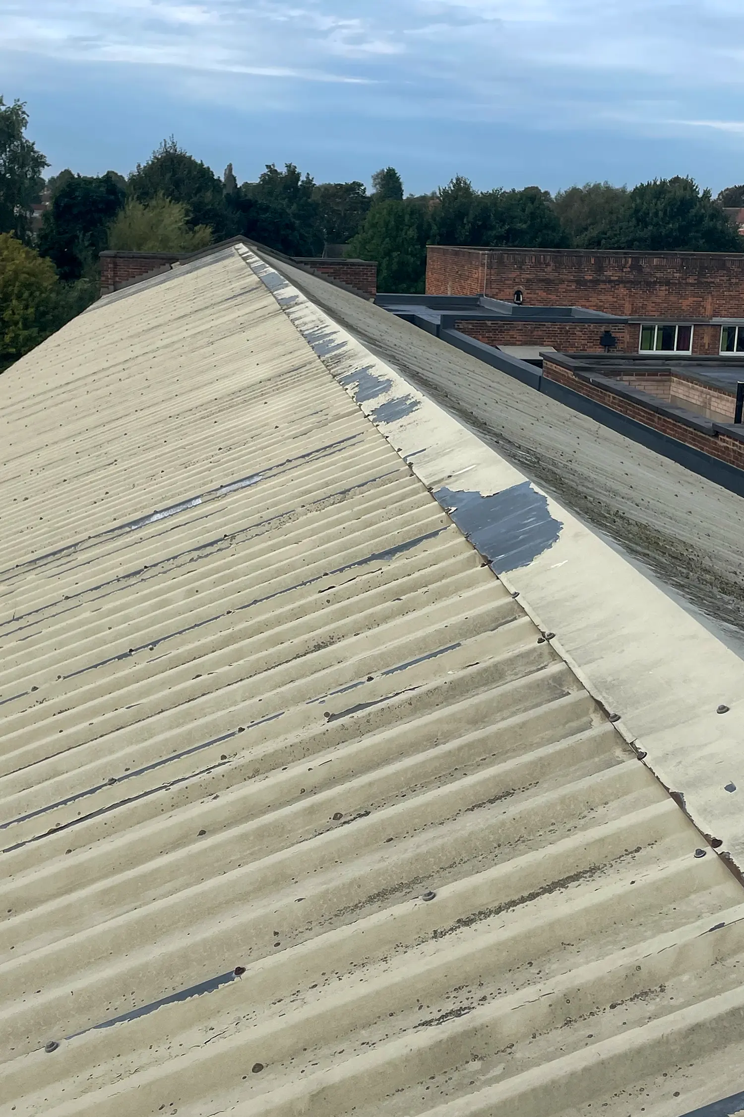 Corrugated metal roof with partial white coating and blue sealing tape strips