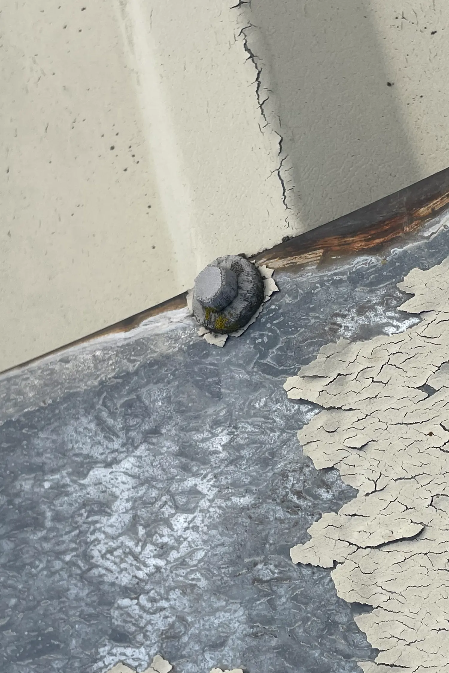 Cracked drywall and peeling paint near wooden beam and metal fastener