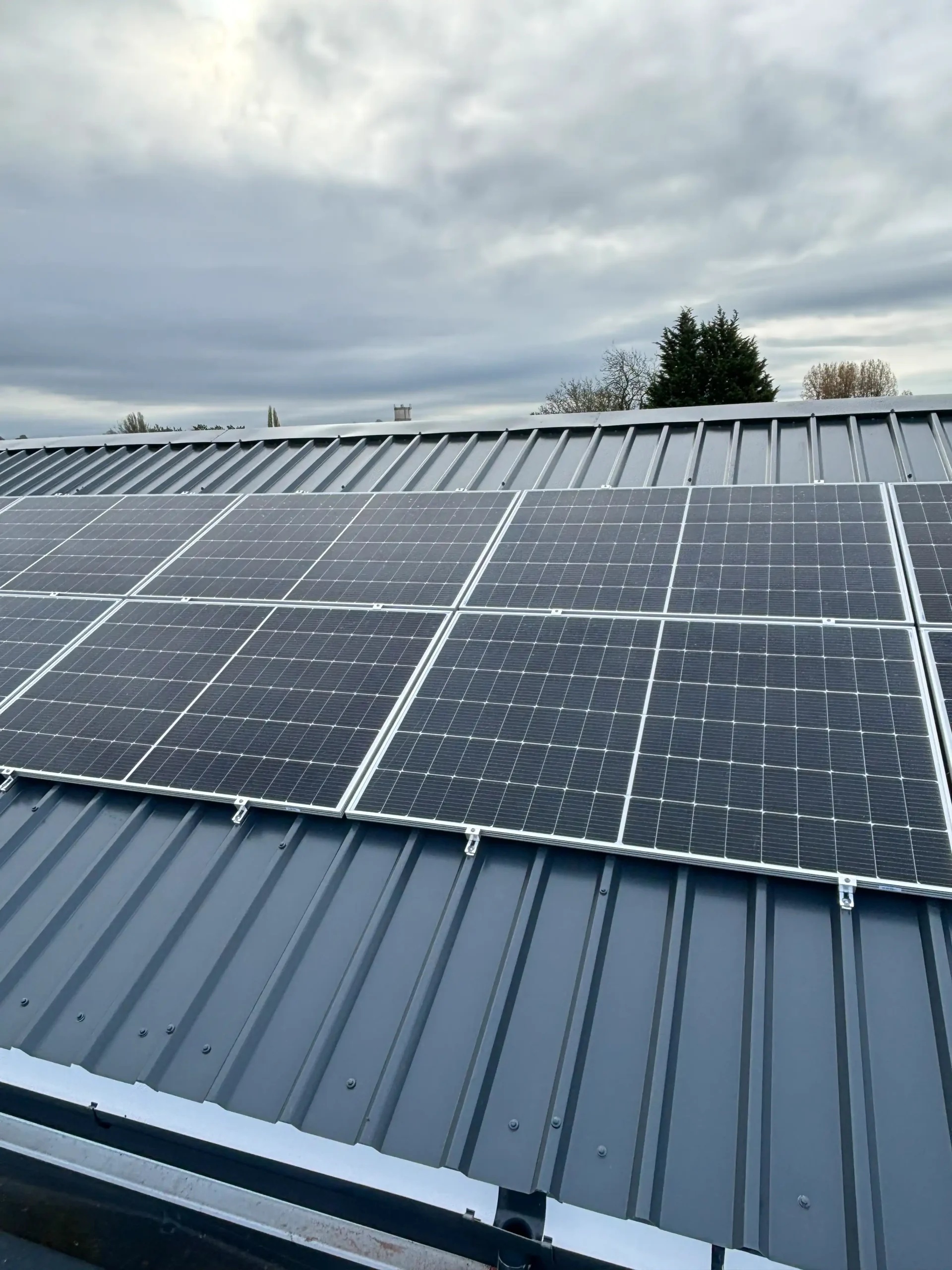 Solar panels installed on metal roof with cloudy sky background