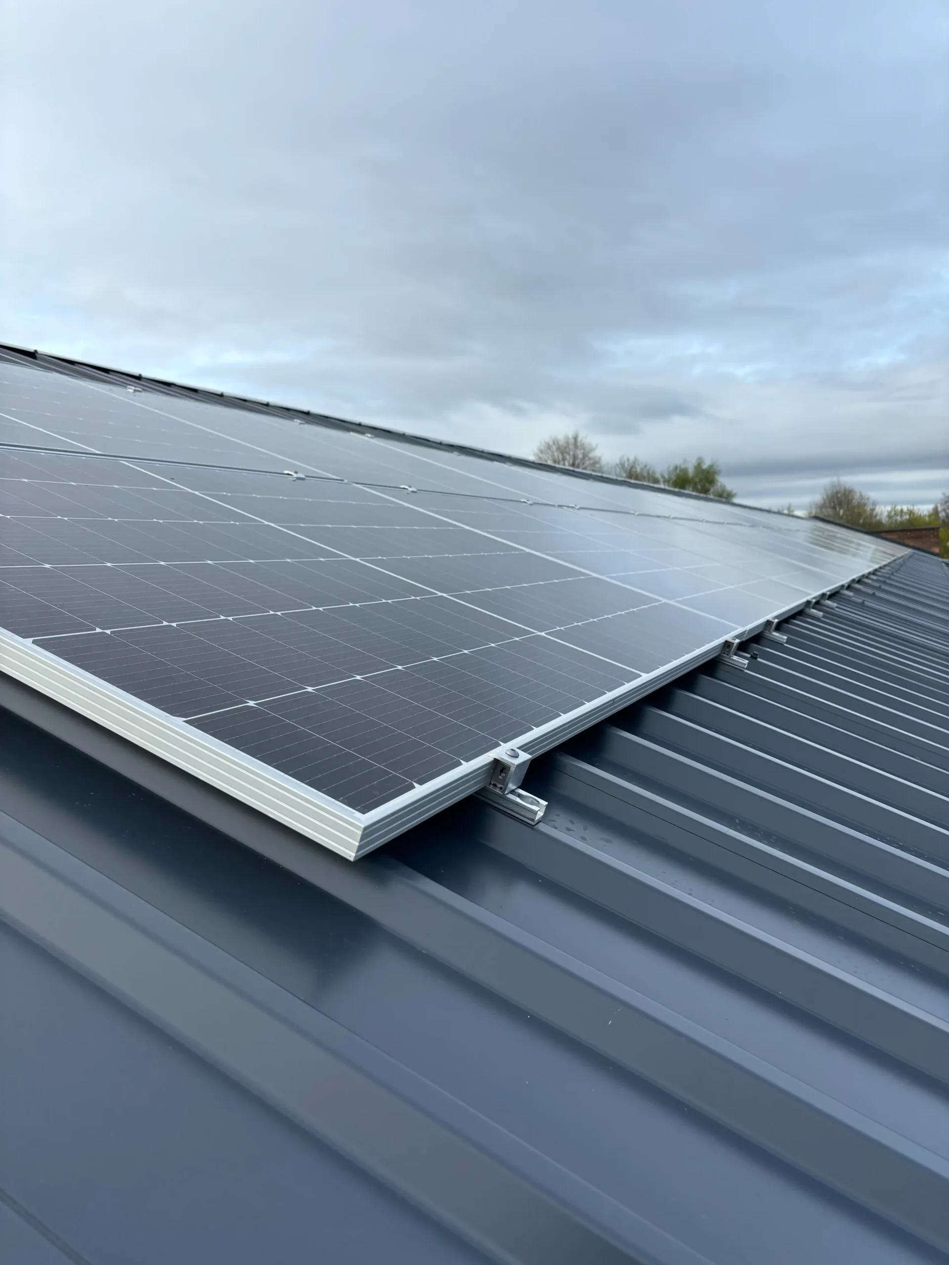 Solar panels installed on corrugated metal roof with cloudy sky