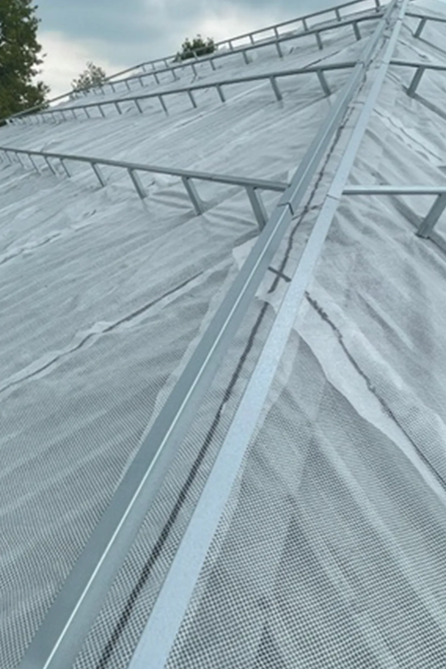 Angled view of white mesh shade cloth covering rugby club roof structure
