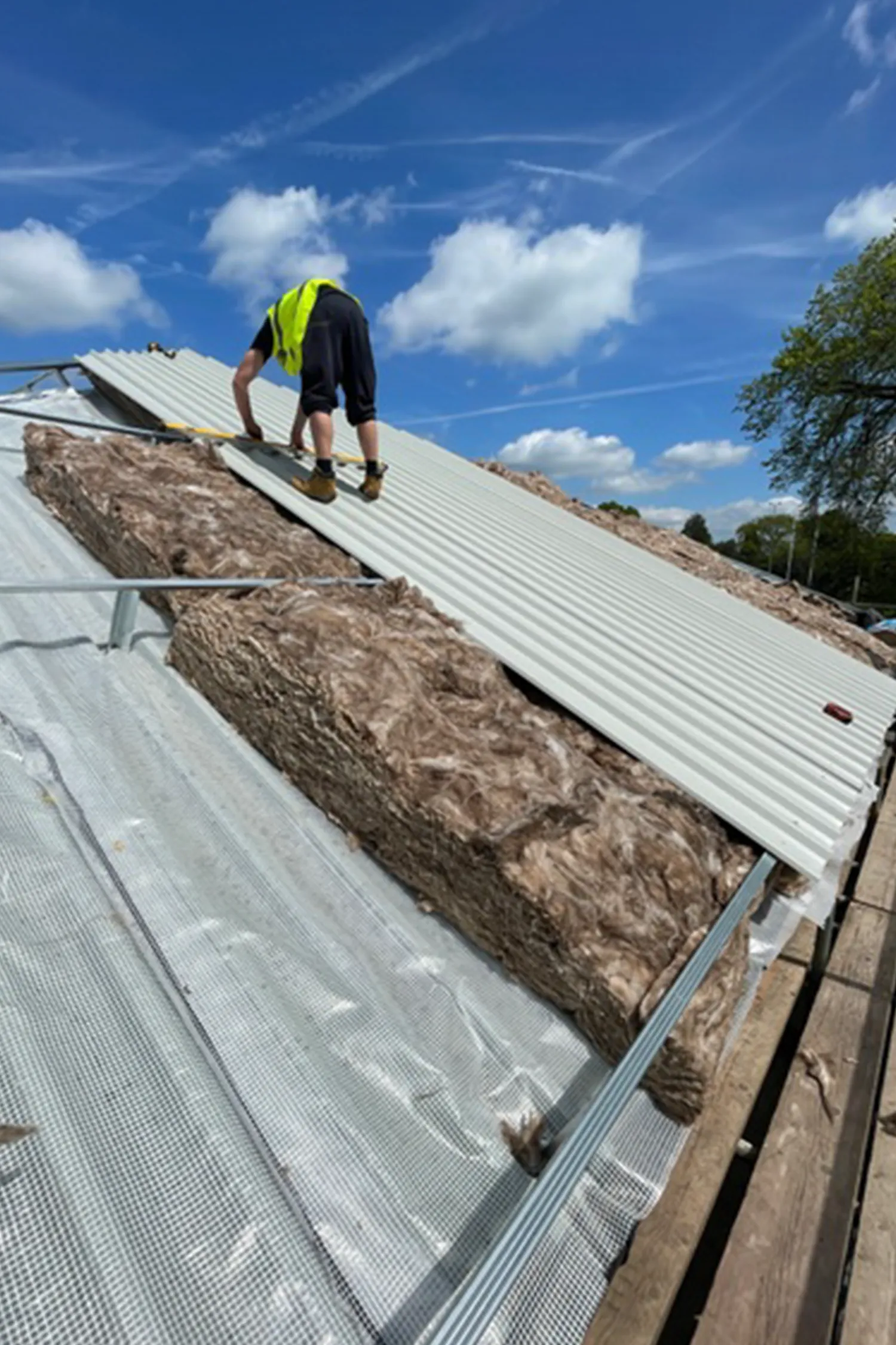 Worker installing metal roofing panels on residential building exterior