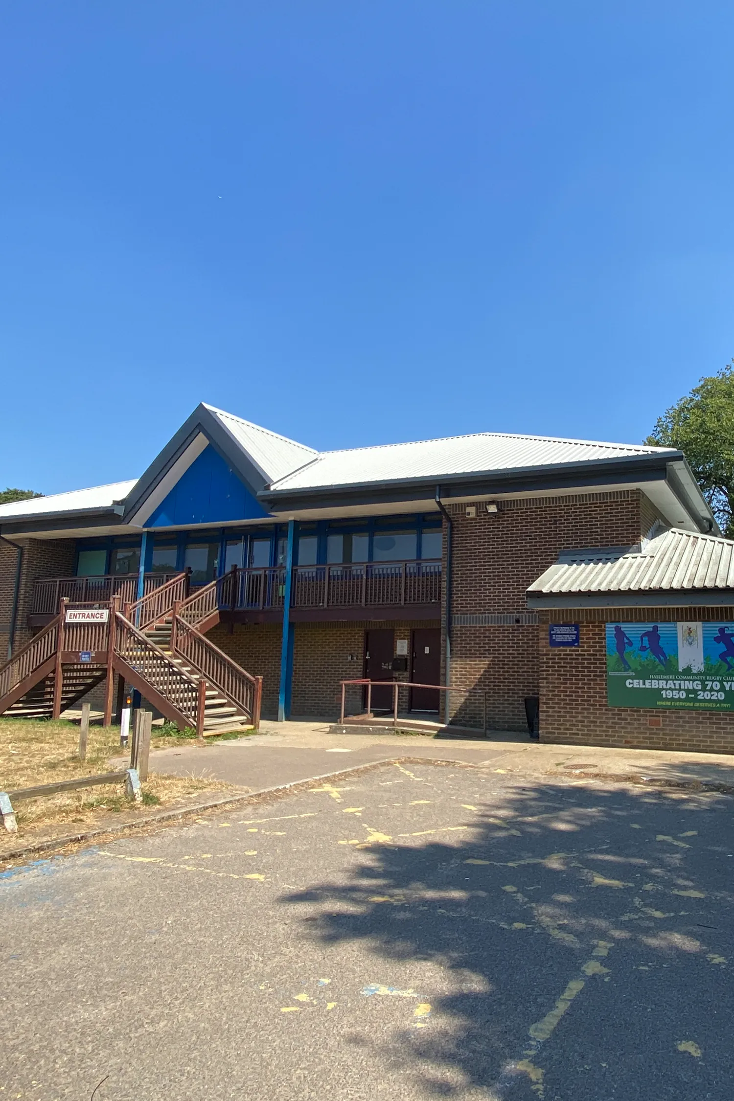 Haslemere Rugby Club brick building with blue roof and wooden entrance ramp