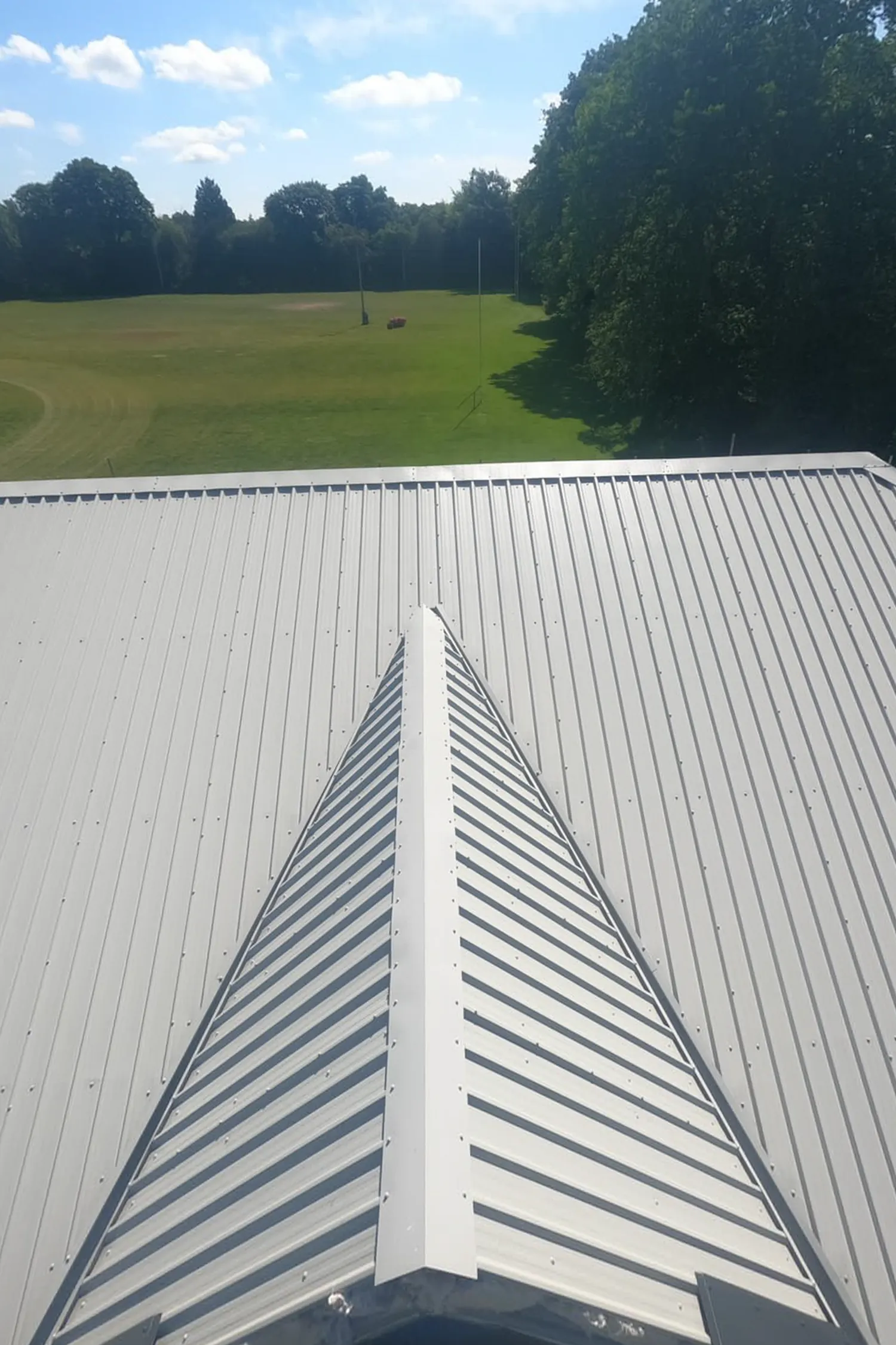 Metal roof with ridge vent overlooking rugby field and trees