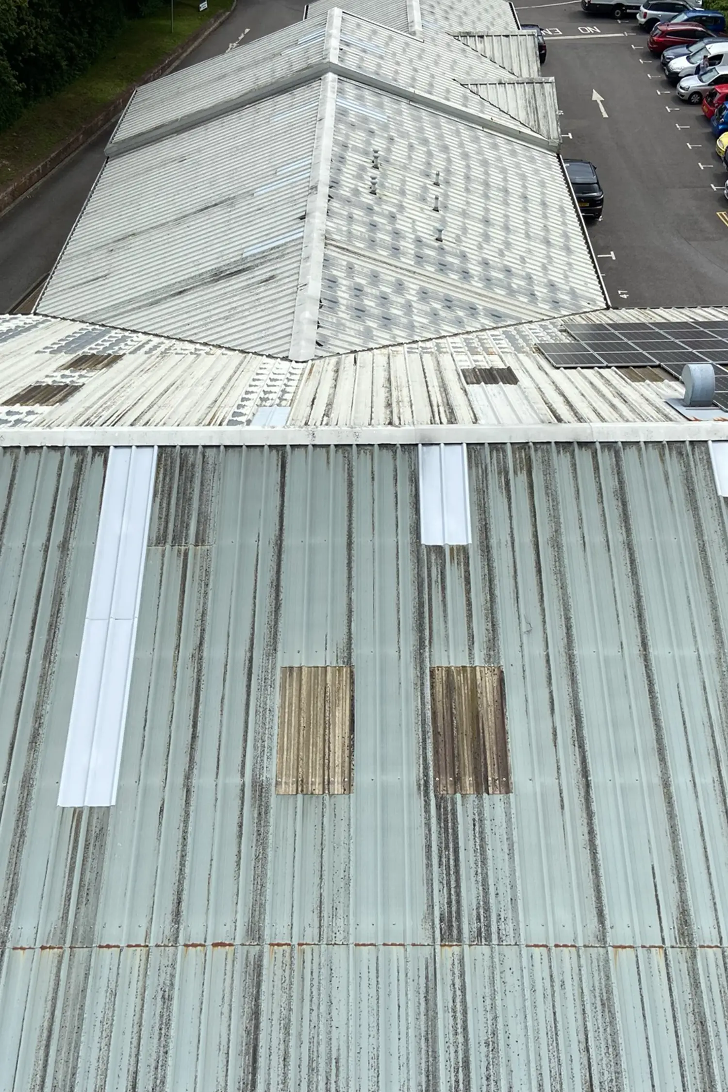 Aerial view metal roof with moss growth and white repair patches