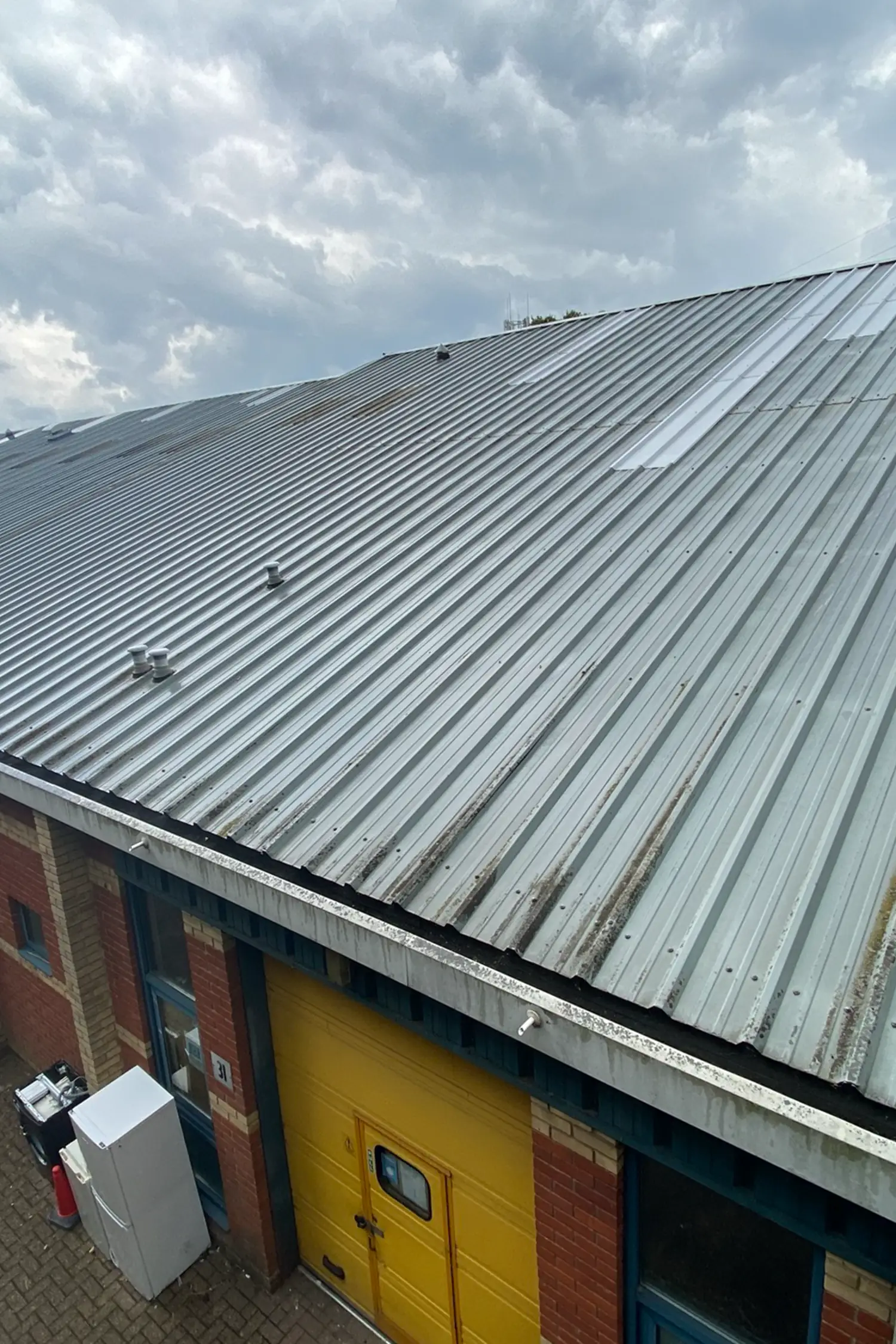 Metal corrugated roof with weathering on brick building structure