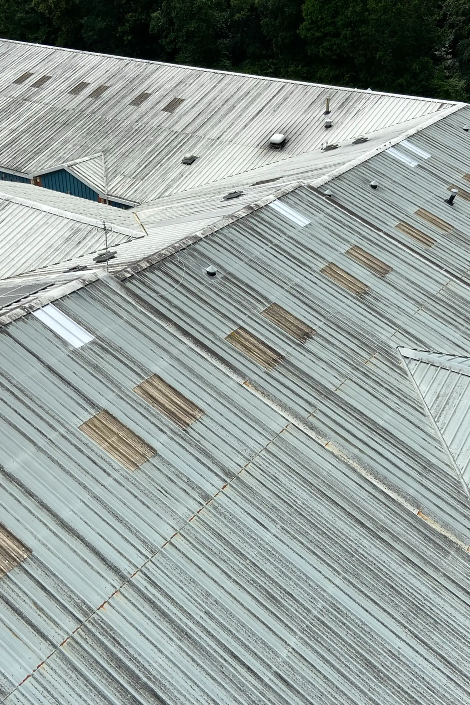 Aerial view of corrugated metal roof with weathered panels and skylights