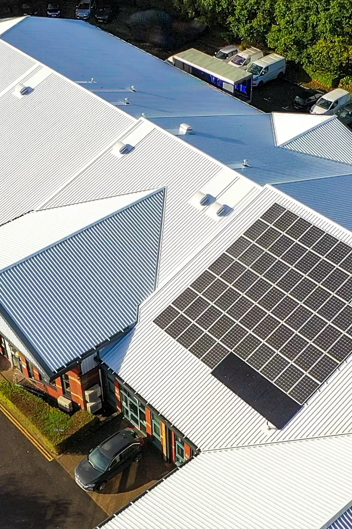 Aerial view of commercial building with solar panels and blue roof coating