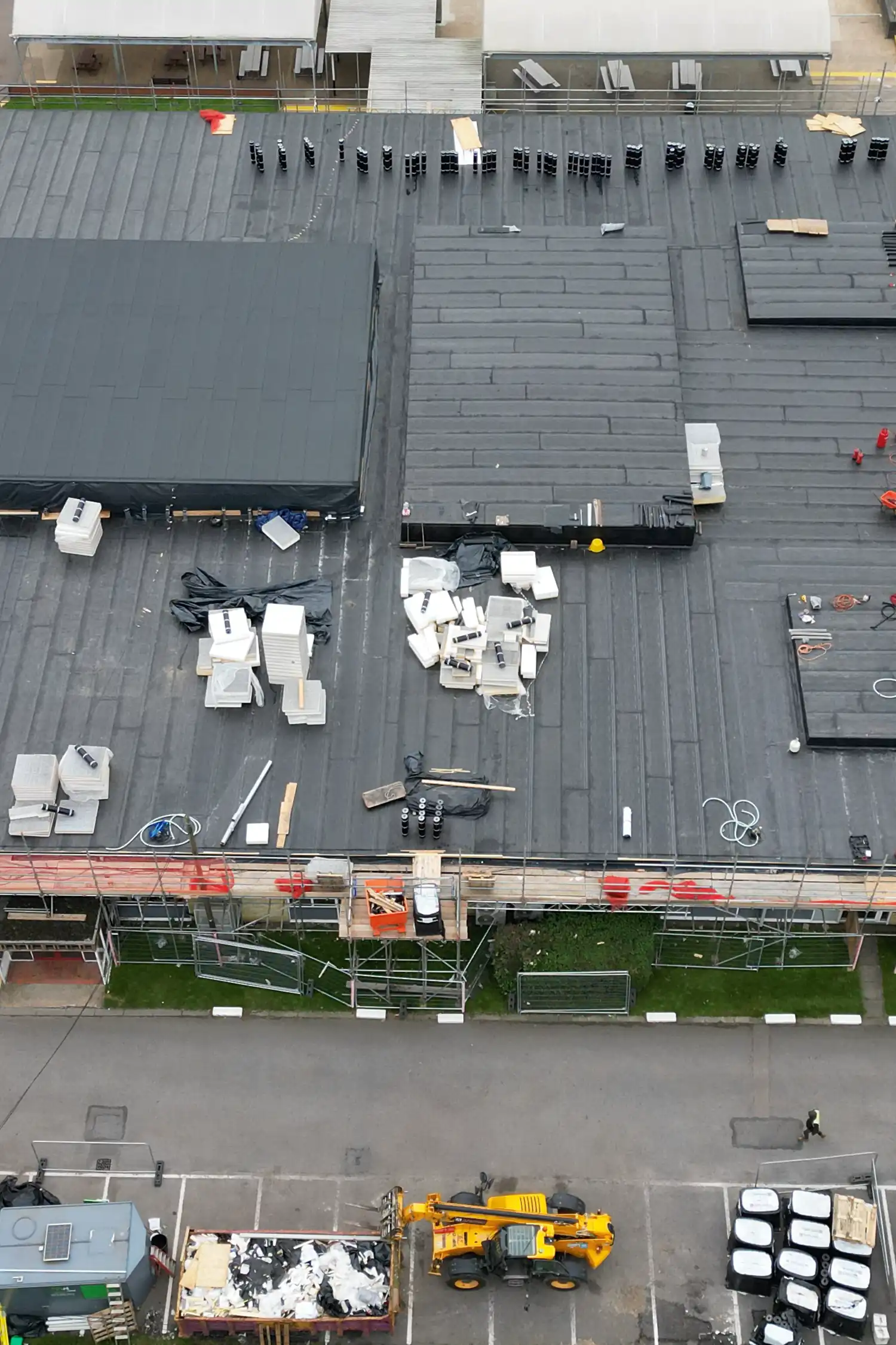 Aerial view of flat roof construction site with materials and equipment staged