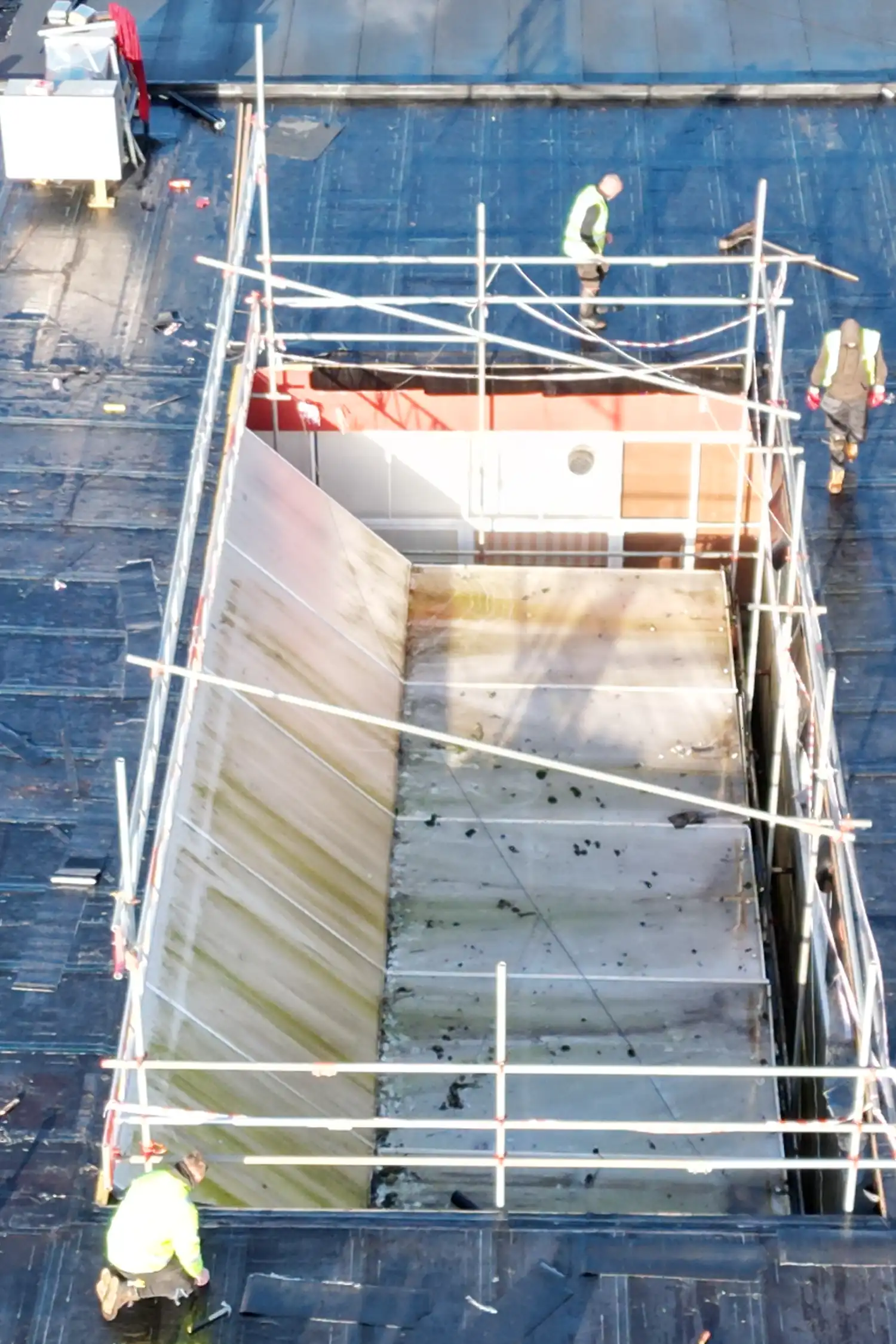 Overhead view of construction workers on metal scaffolding above concrete floor
