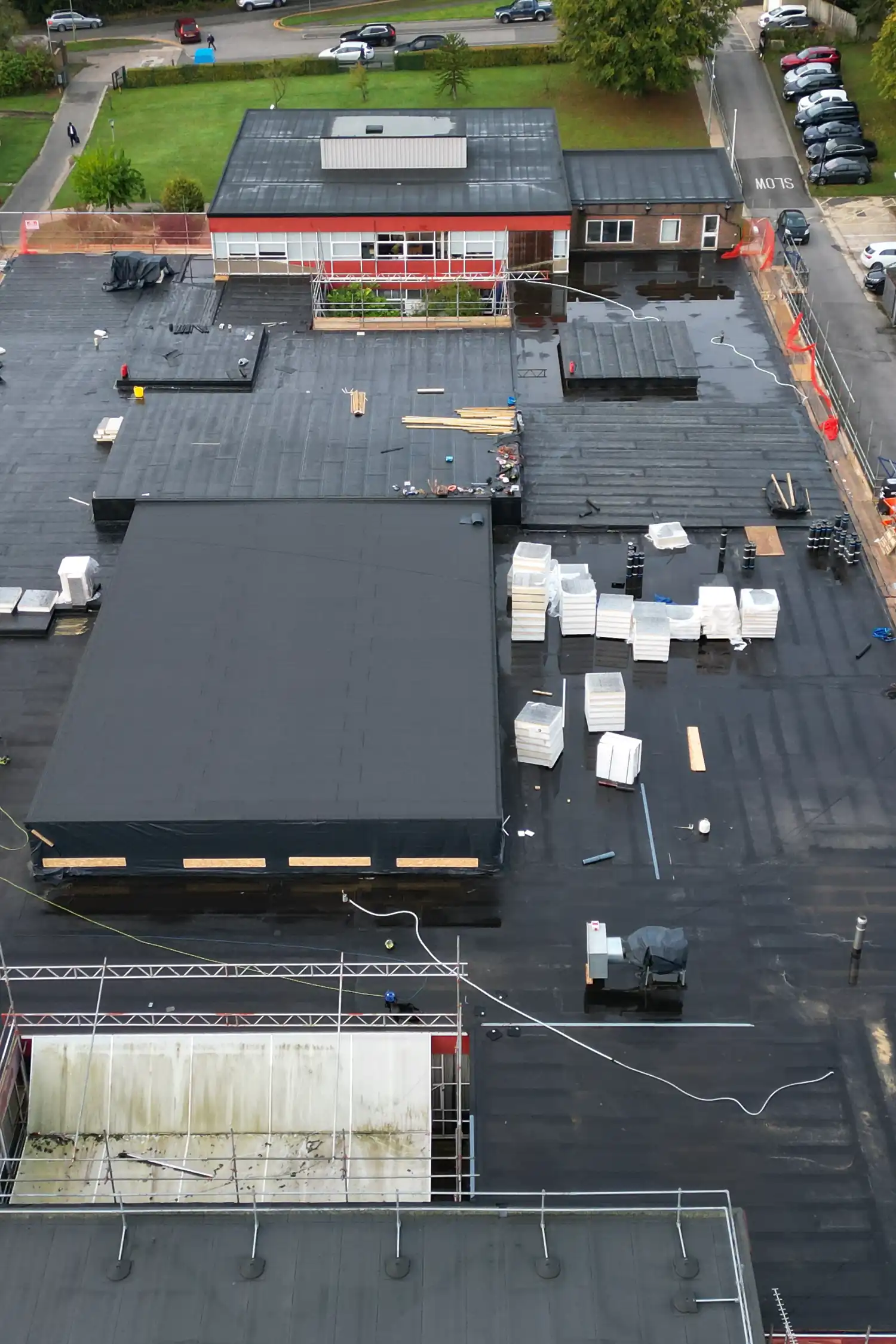 Aerial view of commercial flat roof renovation with materials and equipment staged on surface.