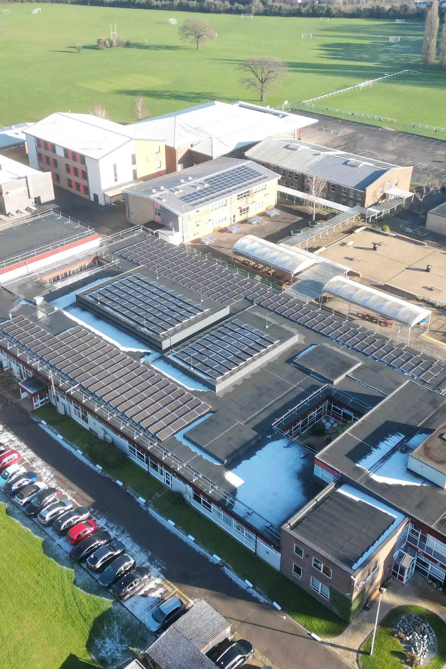 Aerial view of school sports complex with multiple swimming pools and athletic facilities
