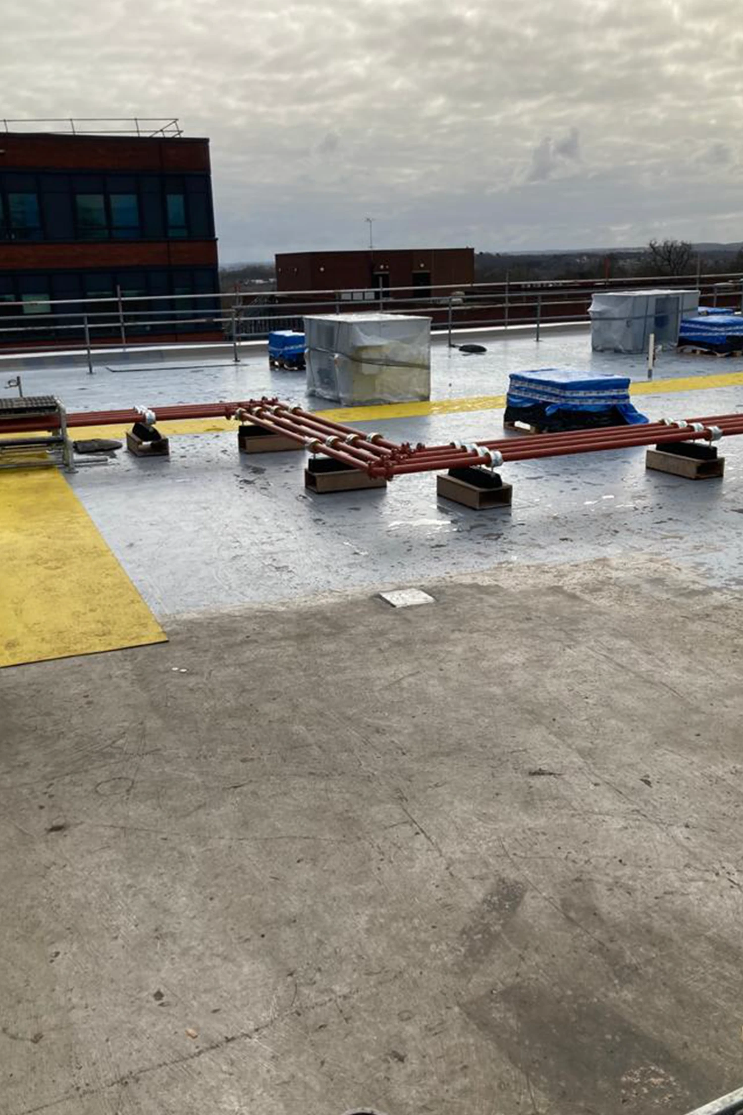 Rooftop construction site with red steel beams and waterproofing materials