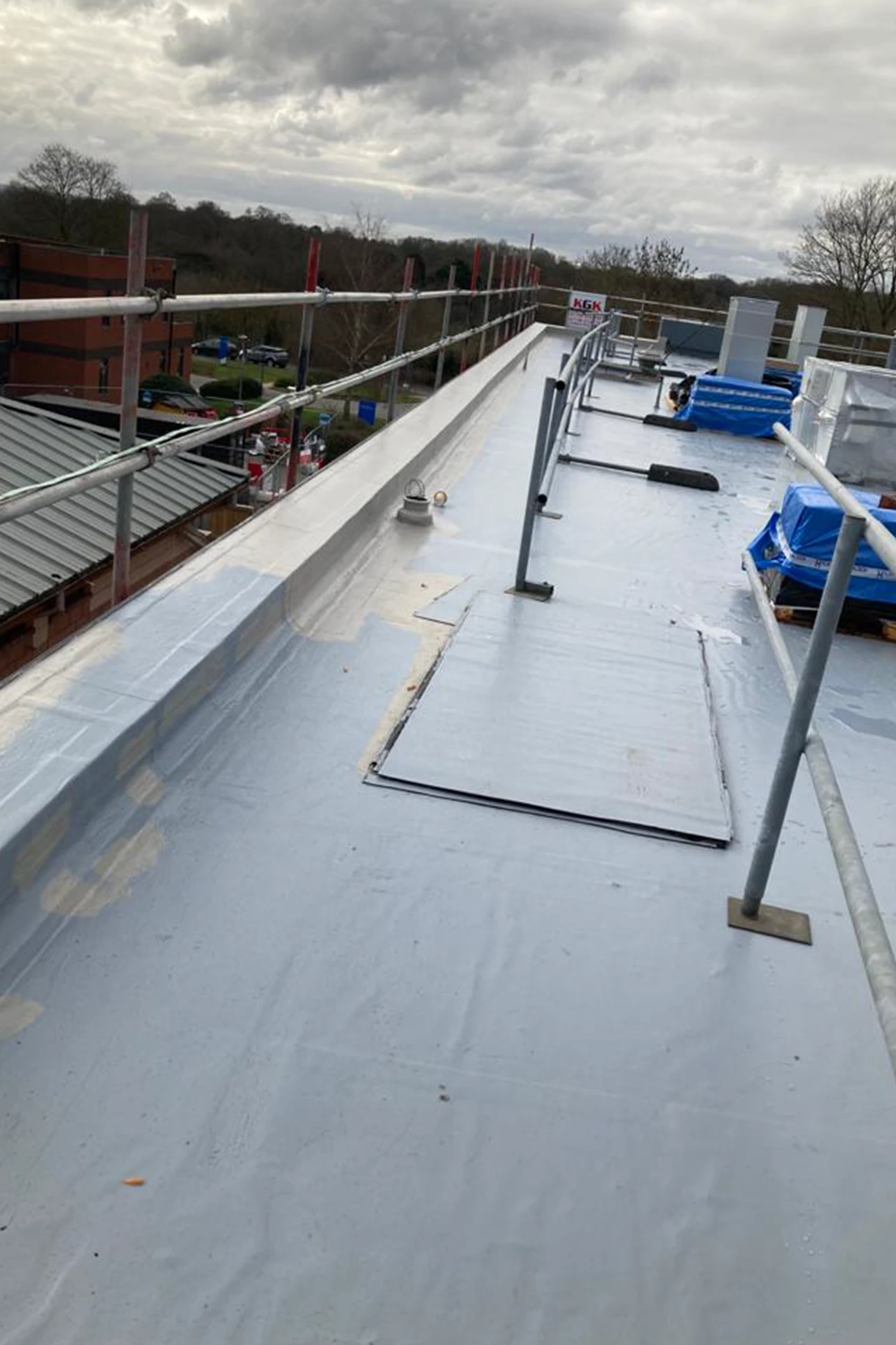 Flat roof waterproofing installation at Queen Mary's Hospital with safety railings