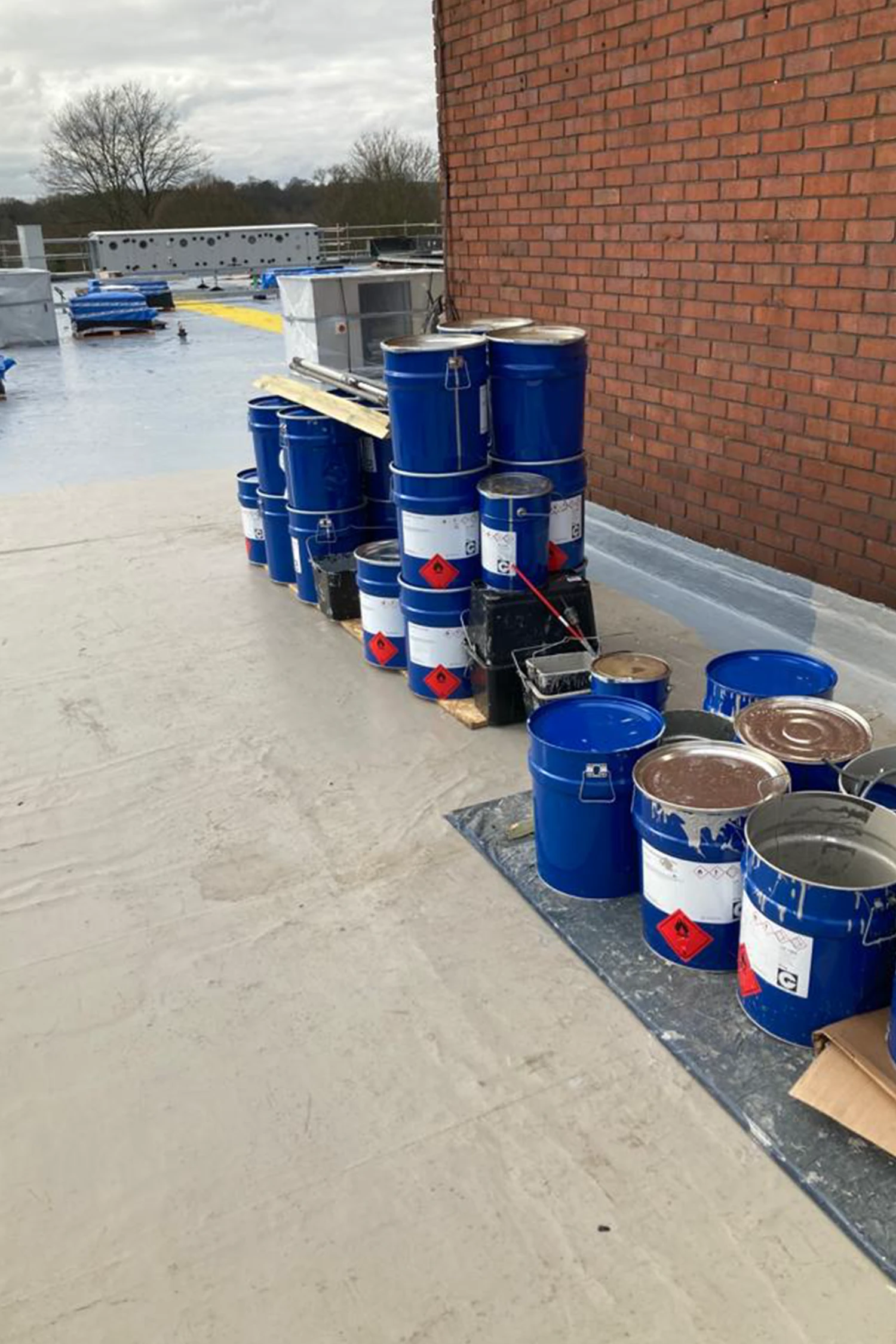 Blue chemical drums with hazard labels arranged on hospital rooftop
