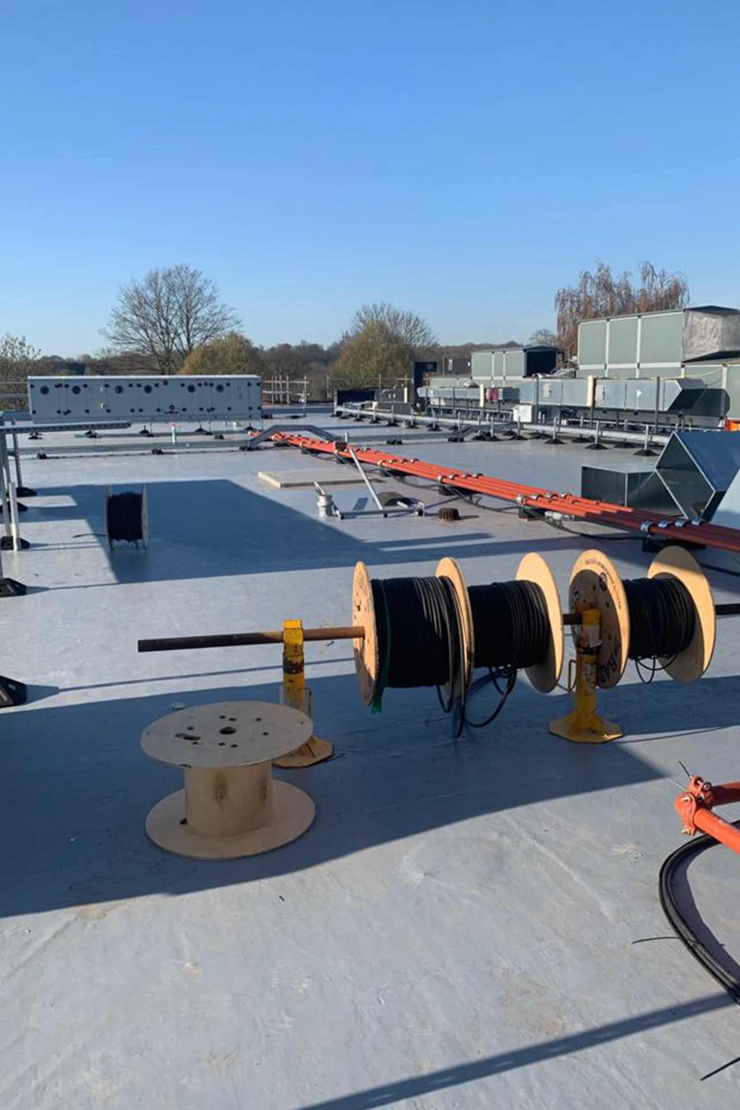 Industrial rooftop with cable reels, waterproofing membrane, and HVAC equipment installation