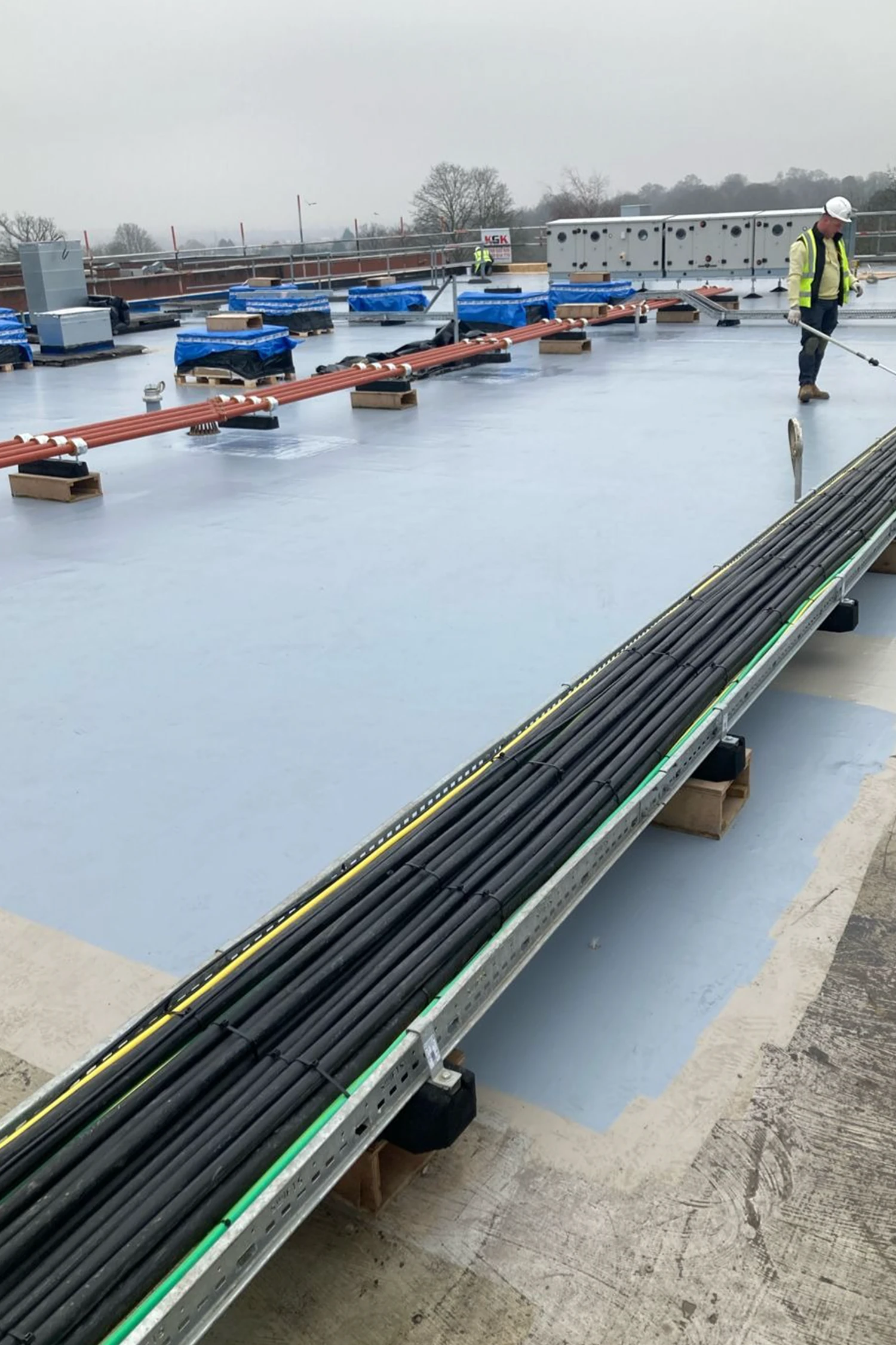 Worker applying liquid waterproofing membrane to commercial flat roof surface