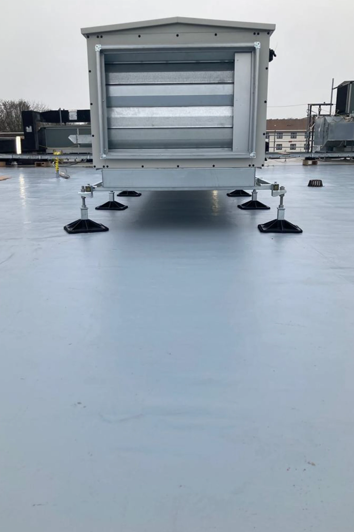 Gray rooftop HVAC unit with horizontal louvers on wet surface