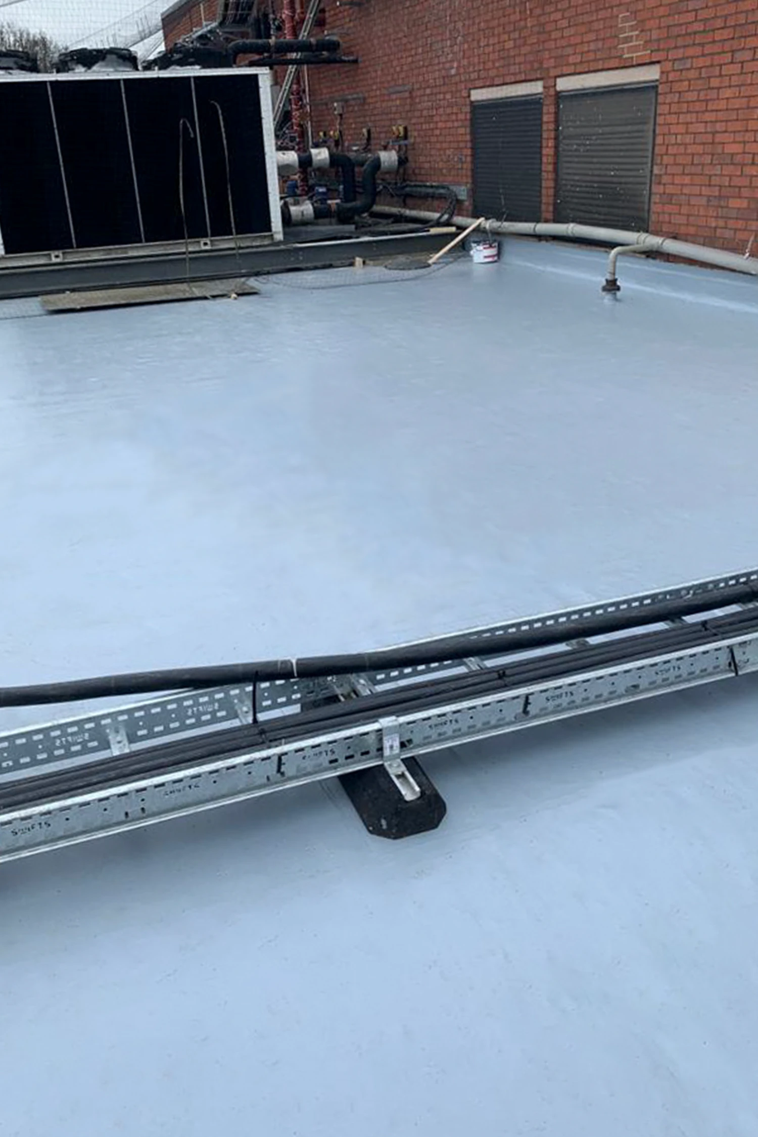 Commercial flat roof waterproofing installation with metal edge trim details