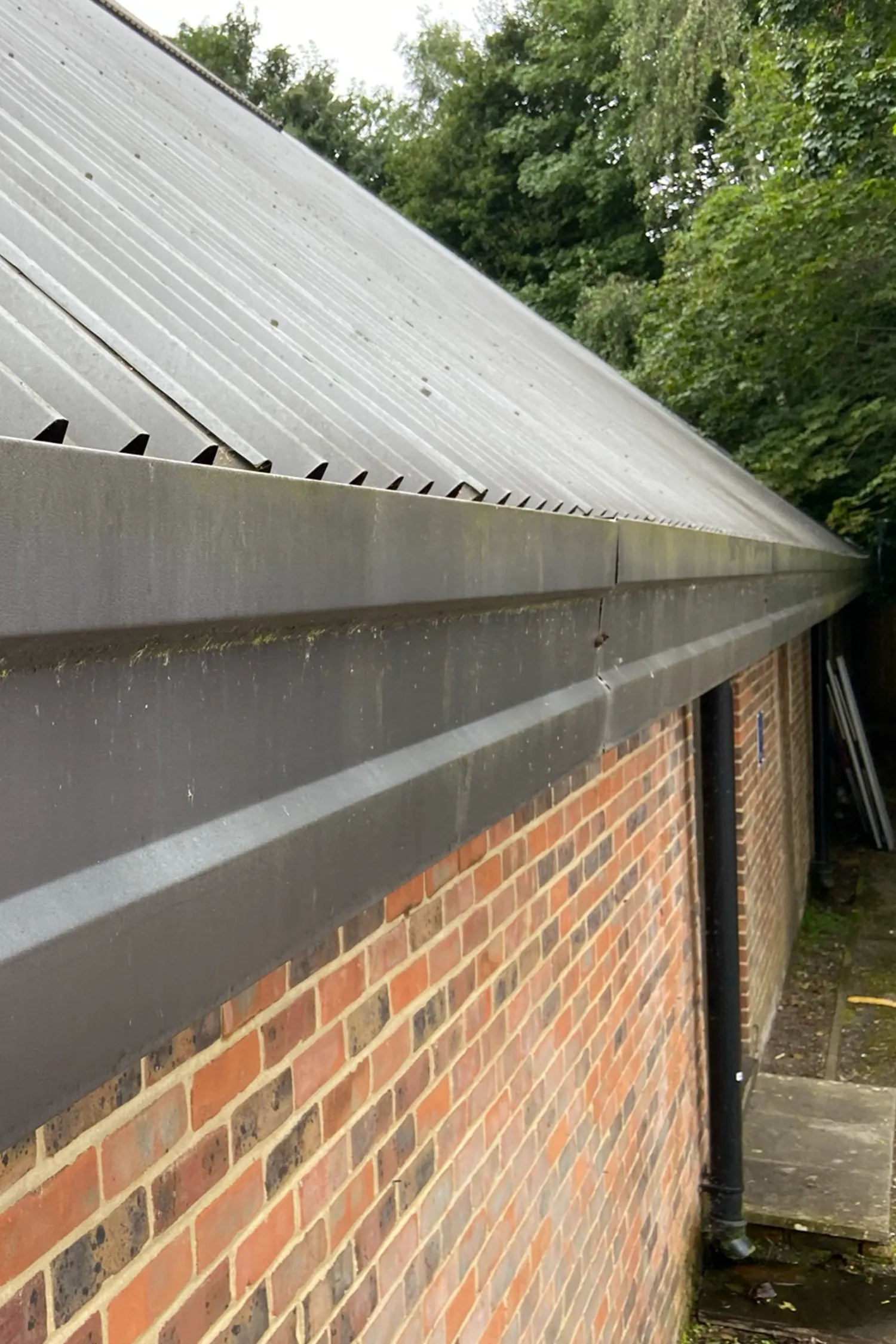 Metal roof cladding on brick building with ventilation gaps