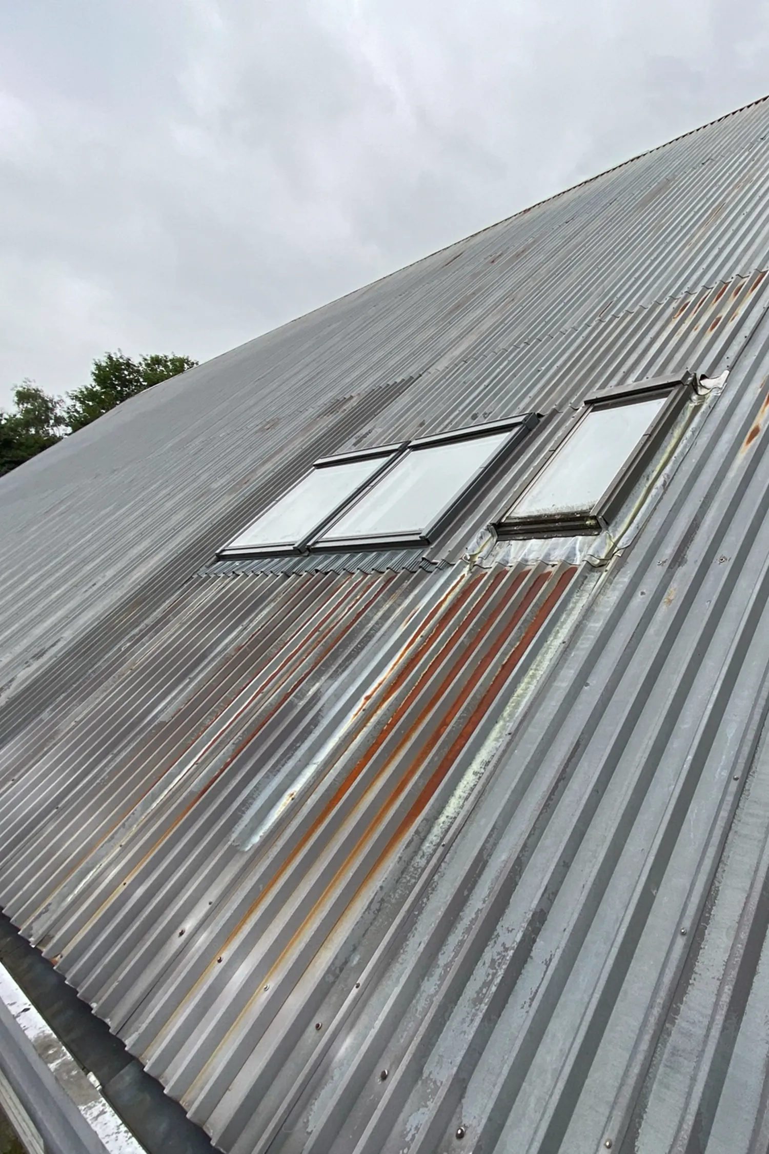 Metal corrugated roof with three skylights installed on steep pitch
