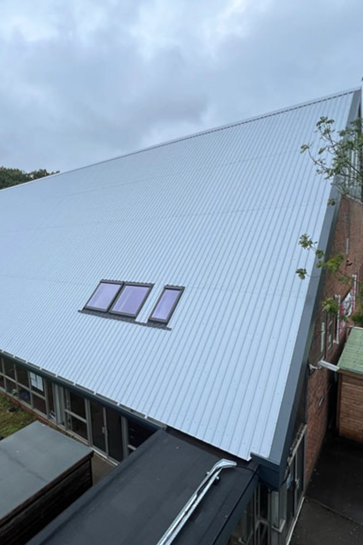 Modern metal roof with three skylights on school sports hall building
