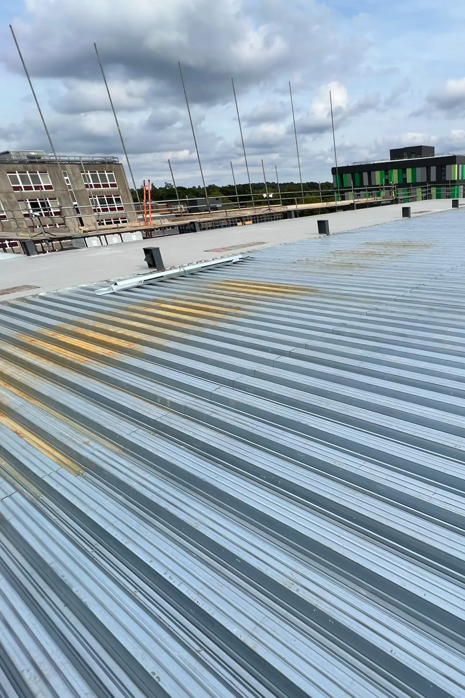 Corrugated metal roofing installation on hospital building under construction with antenna poles