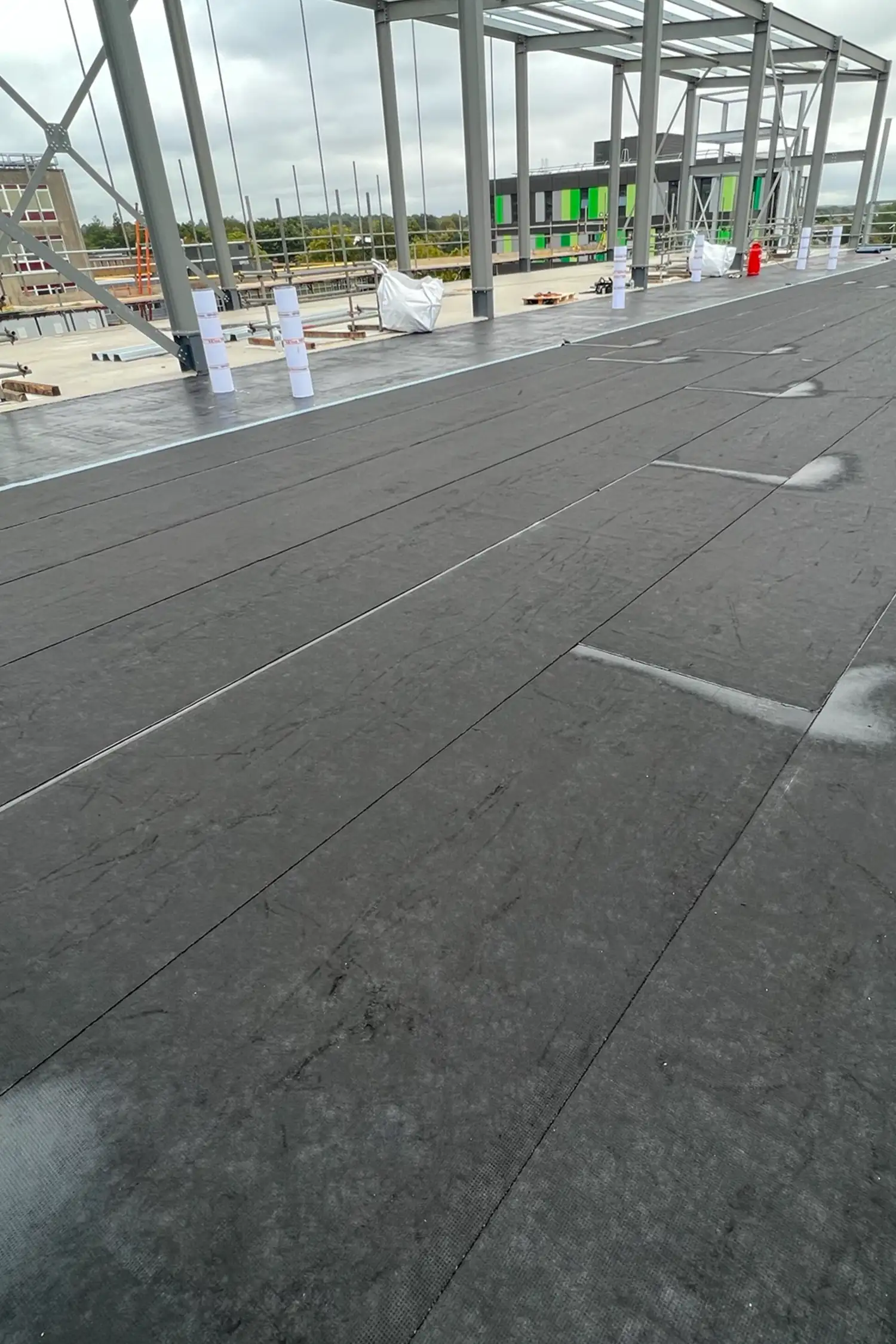 Large concrete floor tiles installed in hospital construction site with steel framework overhead