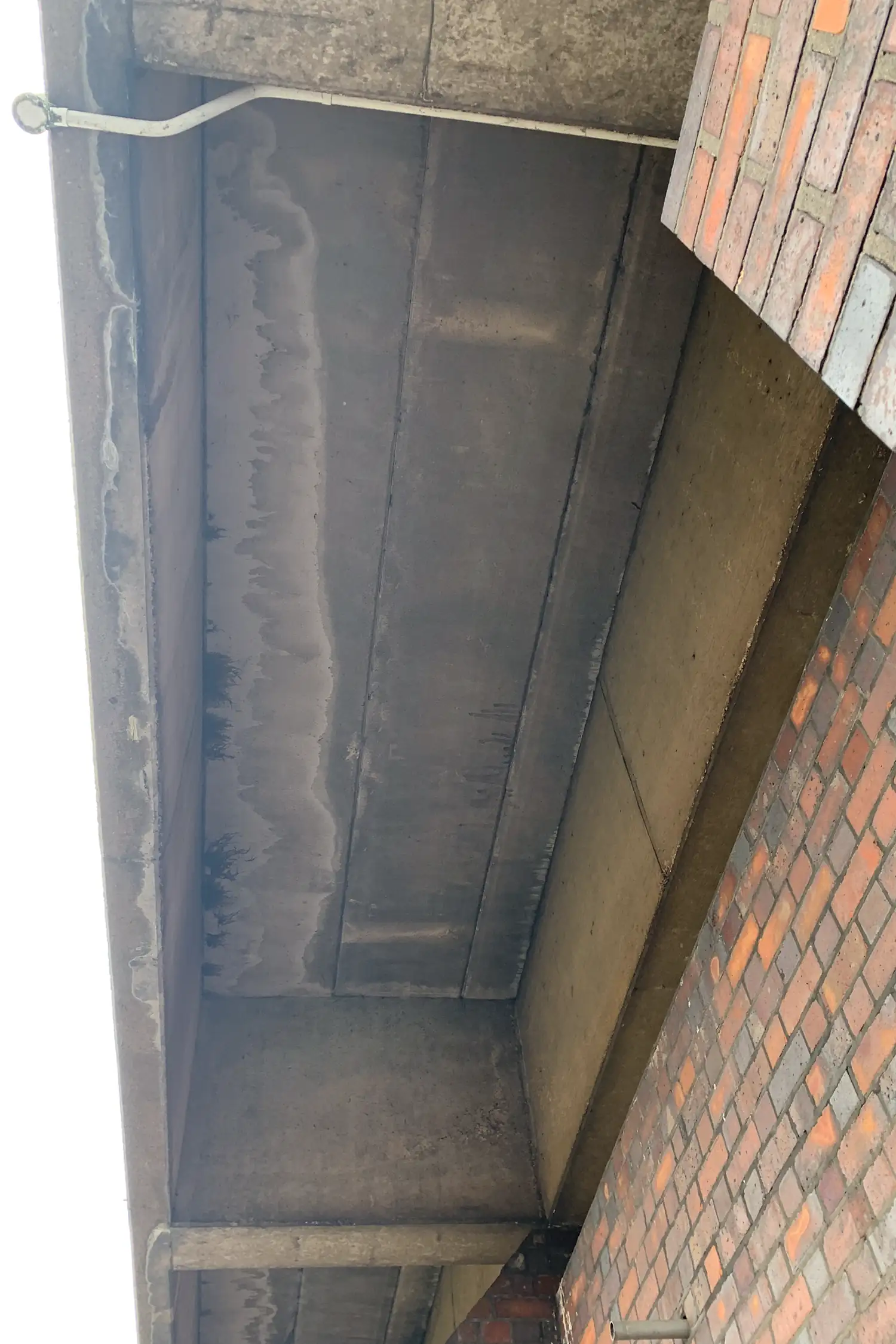 Empty concrete structural cavity with metal support rod and brick wall