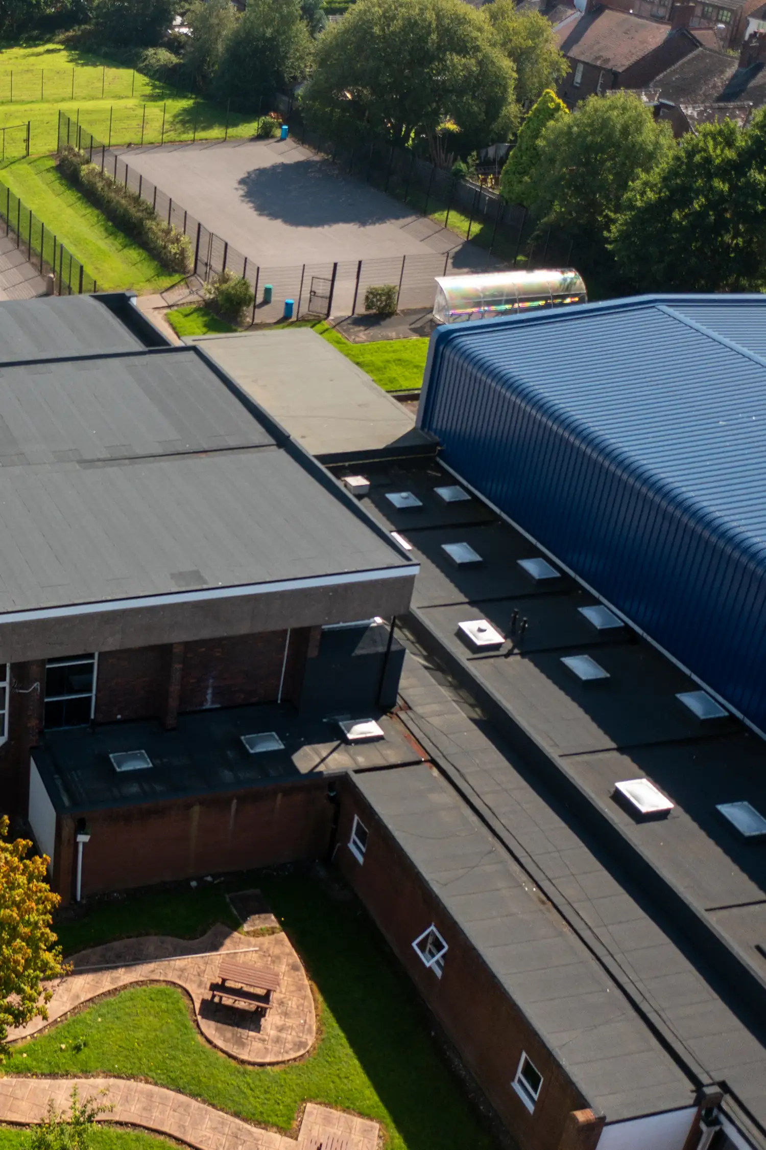 Aerial view of school buildings with blue corrugated roof and playground facilities