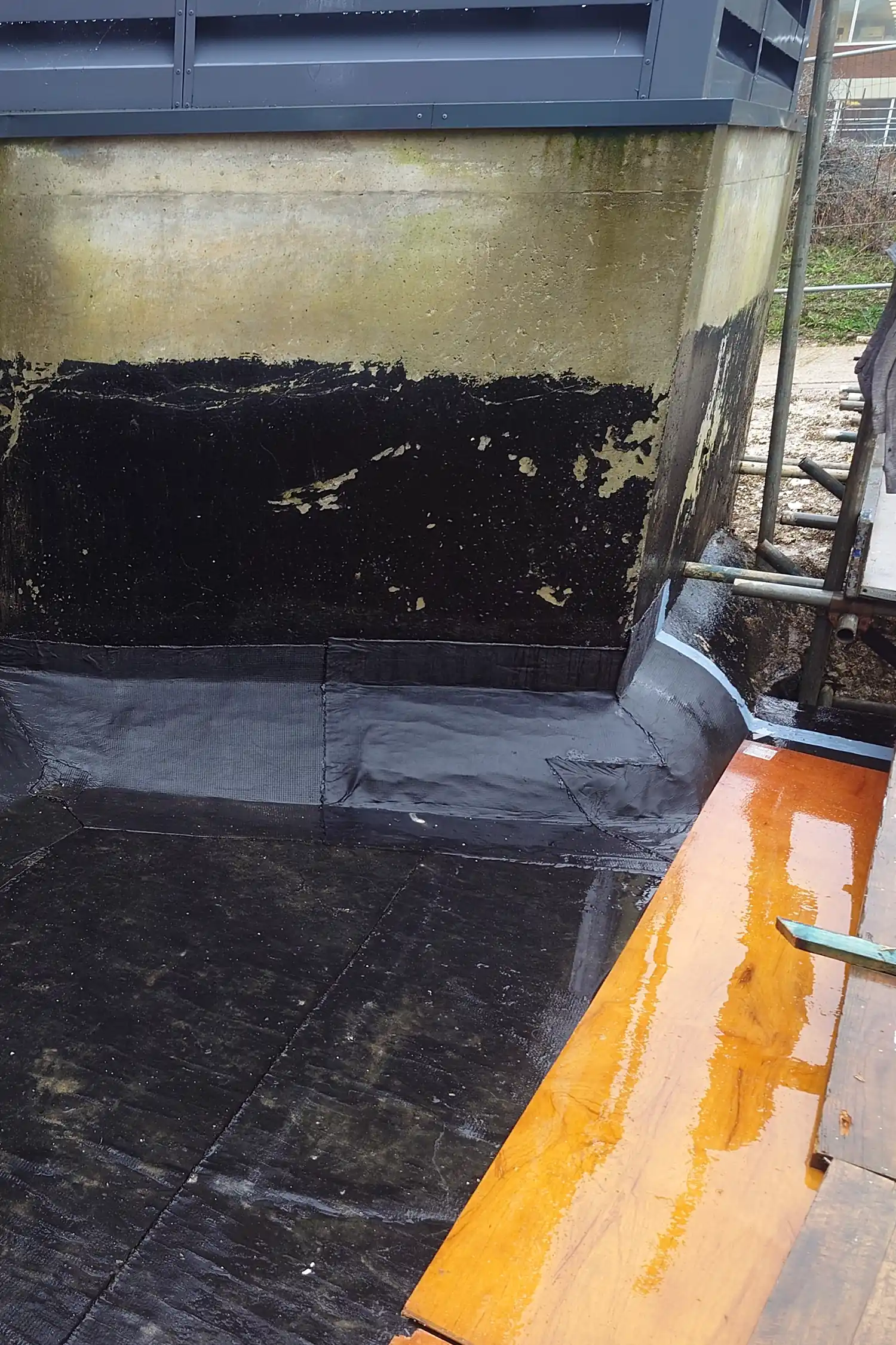 Concrete foundation pit with black waterproof membrane lining installation