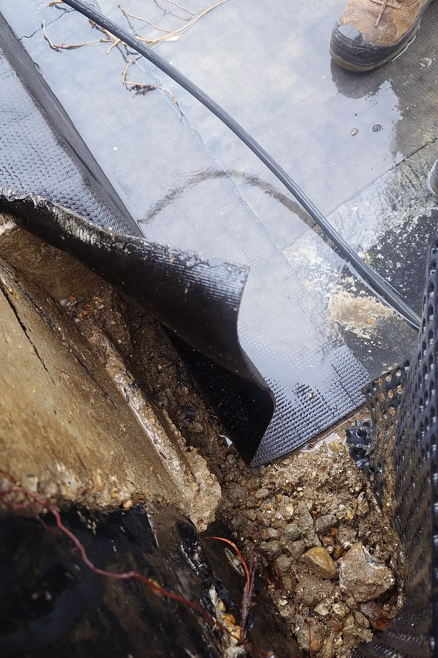 Waterproof membrane installation on building foundation with soil and drainage materials