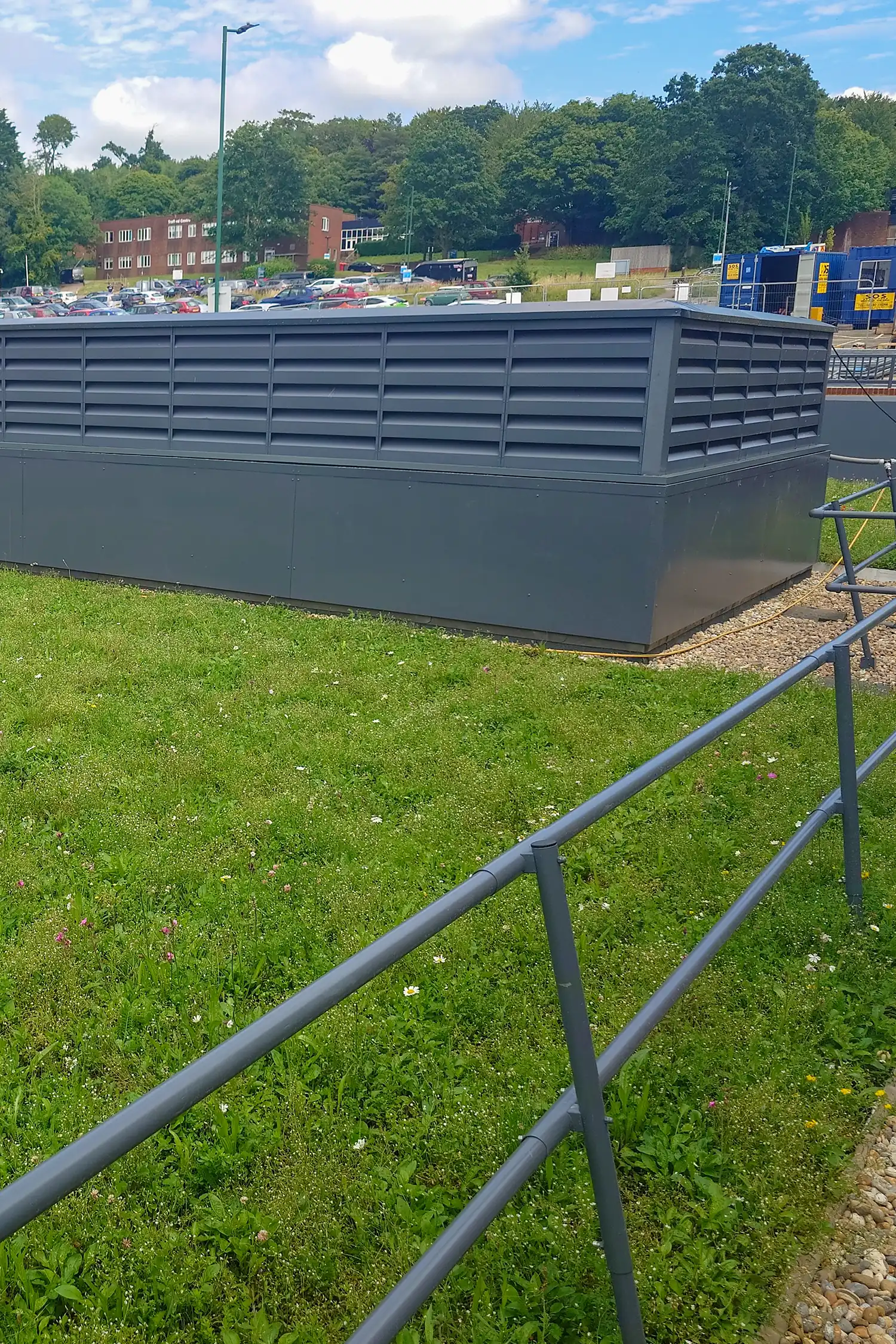 Modern gray metal building with louvered ventilation panels and green roof