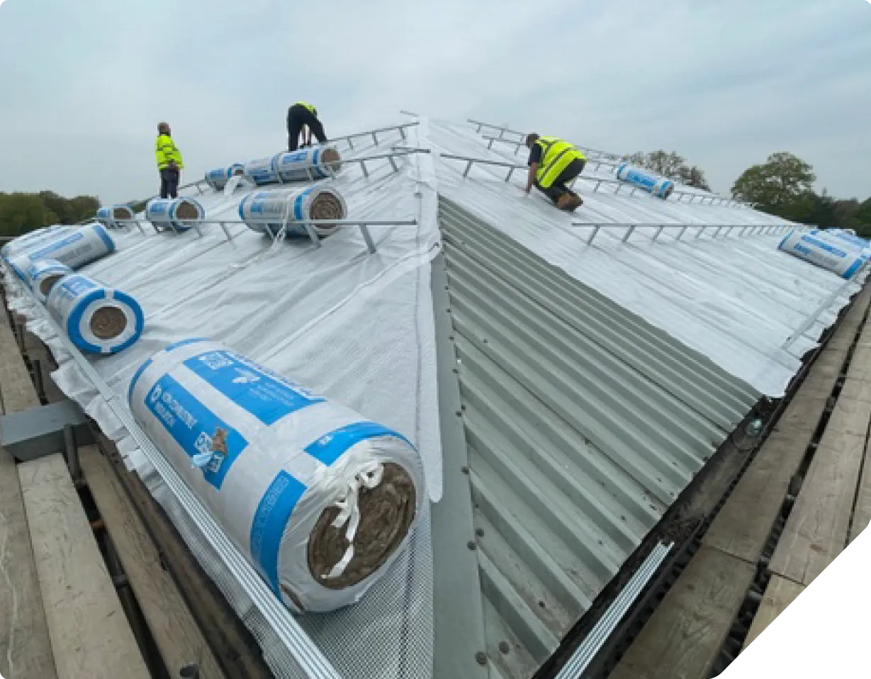 Workers installing solar panels and water tanks on metal roof structure