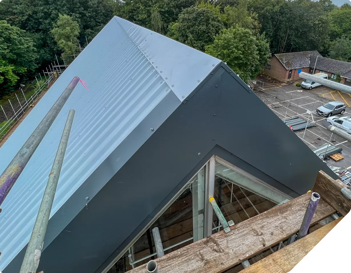 Aerial view of modern school sports hall roof with light blue cladding and dark fascia panels