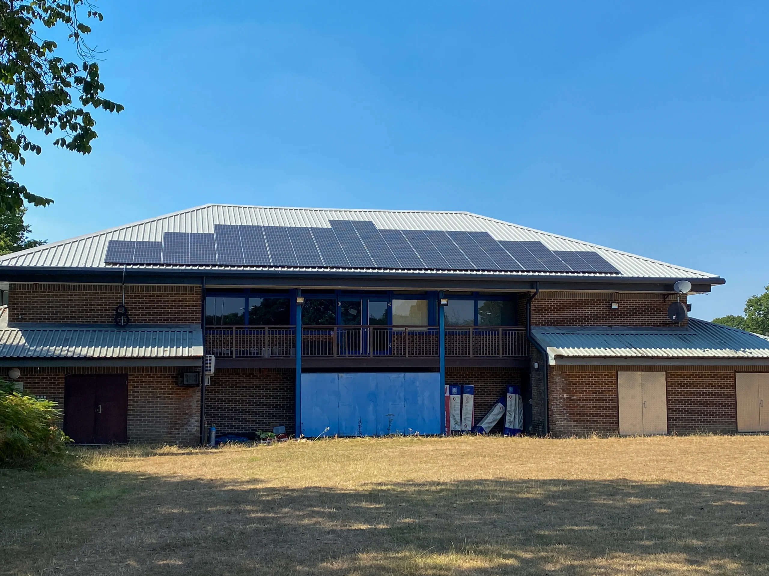 Brick building with solar panels and blue doors at rugby club
