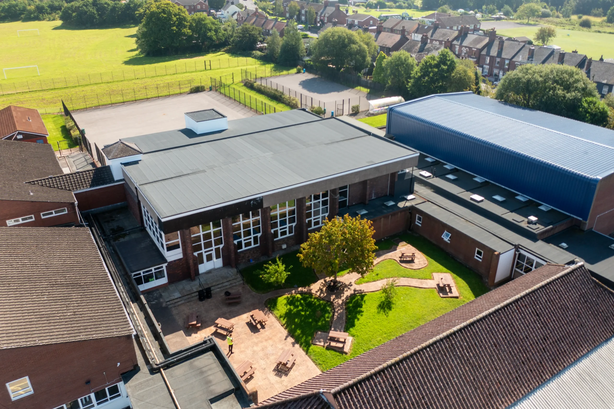 Aerial view of modern school building with courtyard playground and sports fields