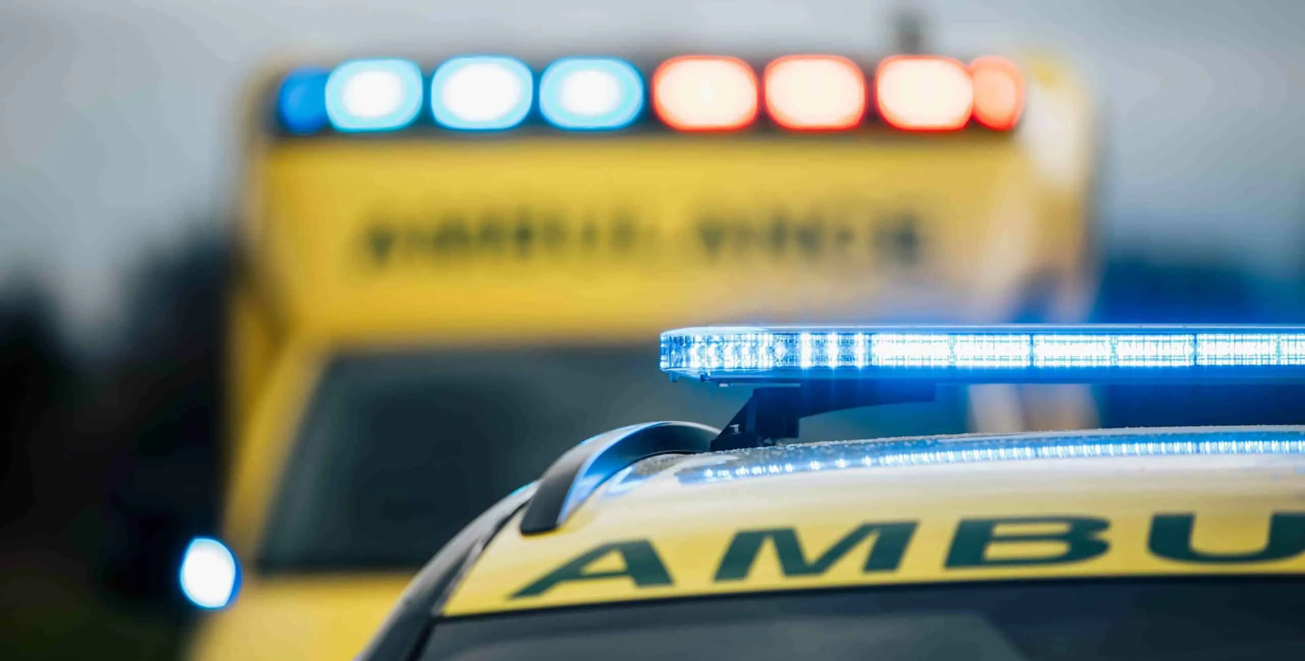 Emergency vehicle with blue light bar and yellow Ambulance markings visible