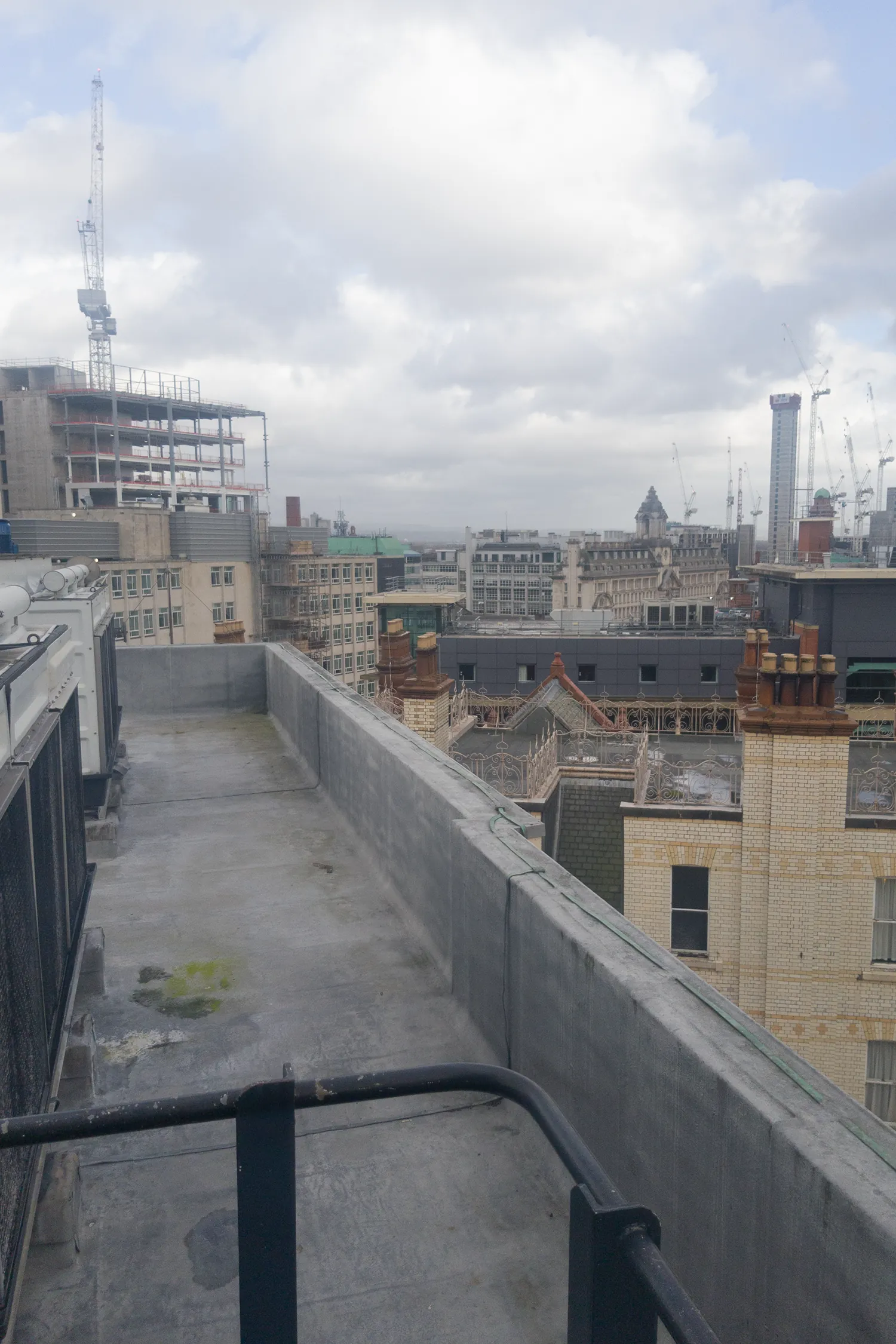 Rooftop terrace overlooking London cityscape with construction cranes and historic buildings