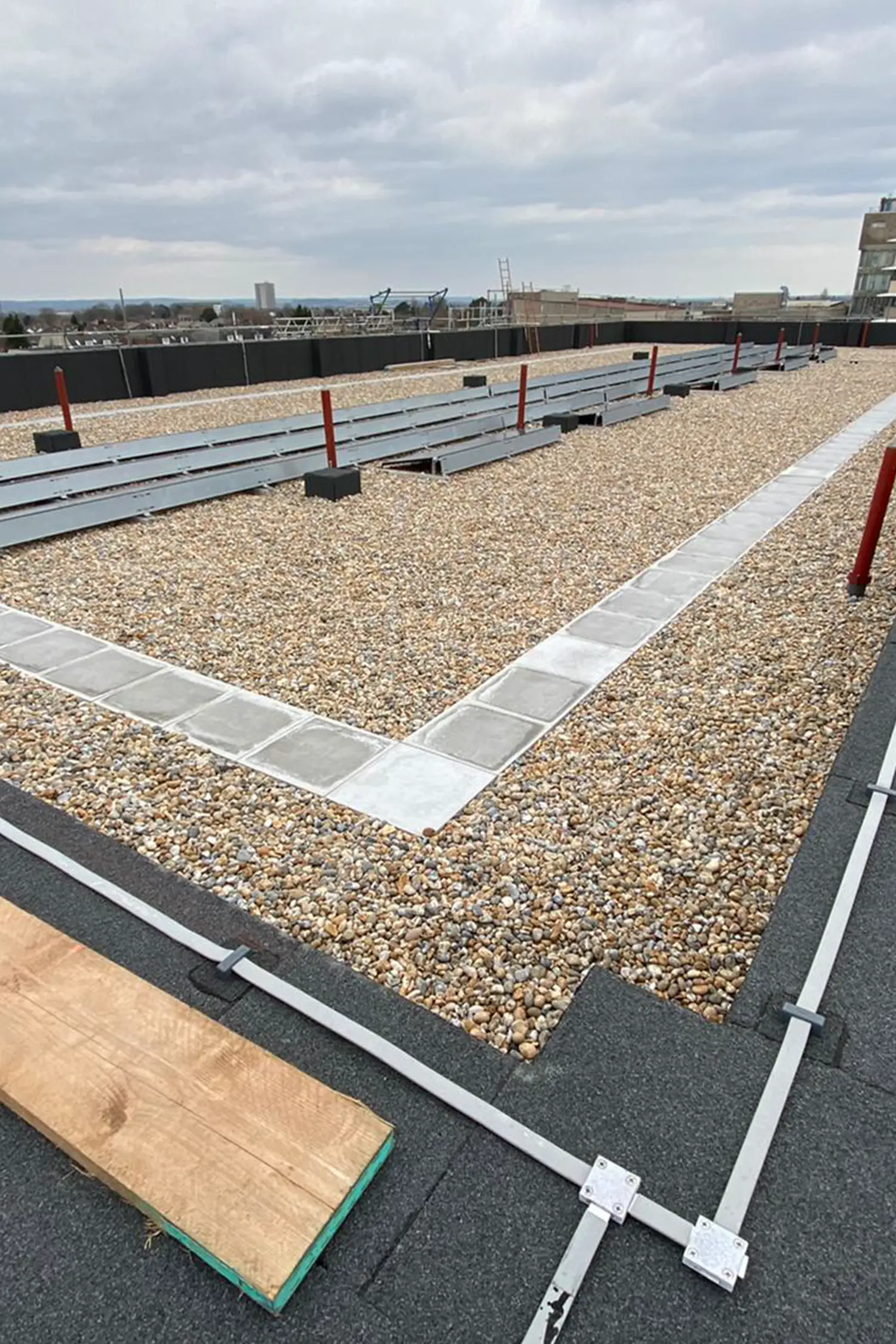 Rooftop construction site with gravel, metal beams, and red support posts
