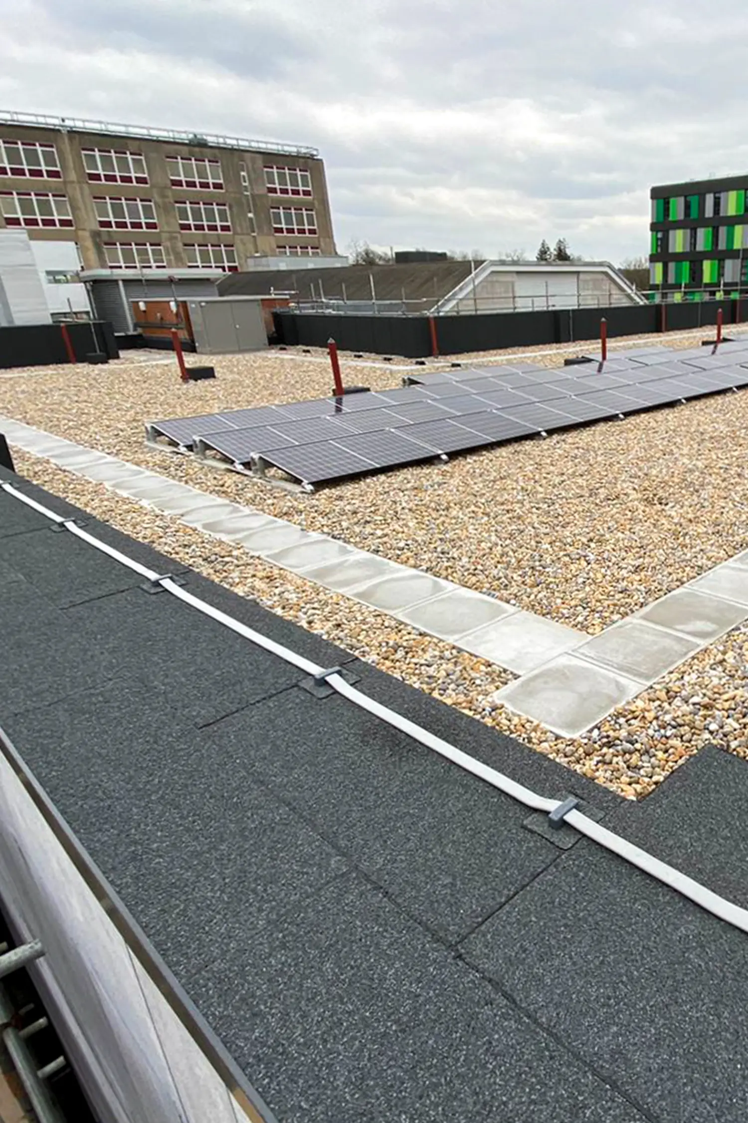 Rooftop solar panels installation on modern hospital building with gravel surface