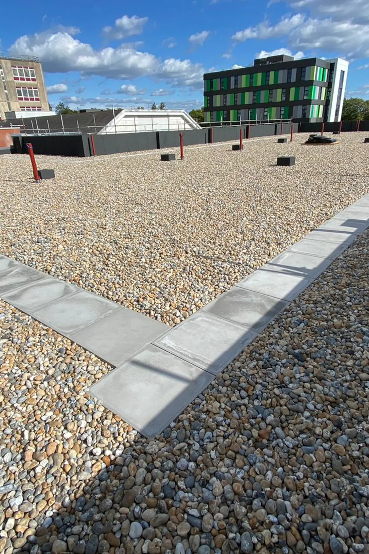 Modern oncology ward courtyard with gravel pathways and contemporary green building architecture.